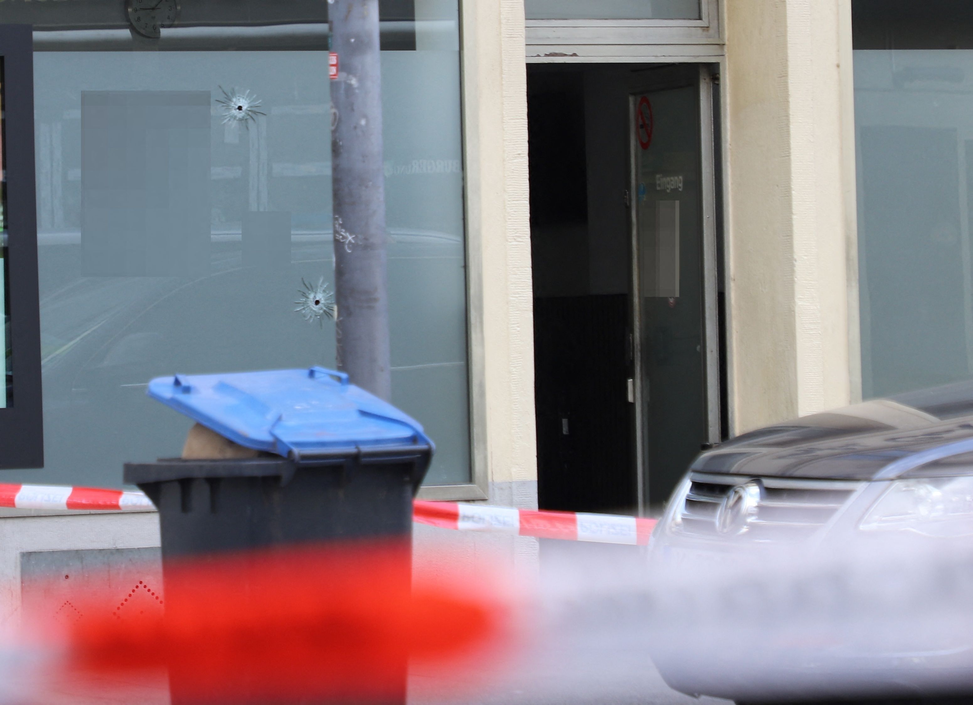 Einschusslöcher sind hinter einer Absperrung an der Fensterscheibe eines Cafés zu sehen.