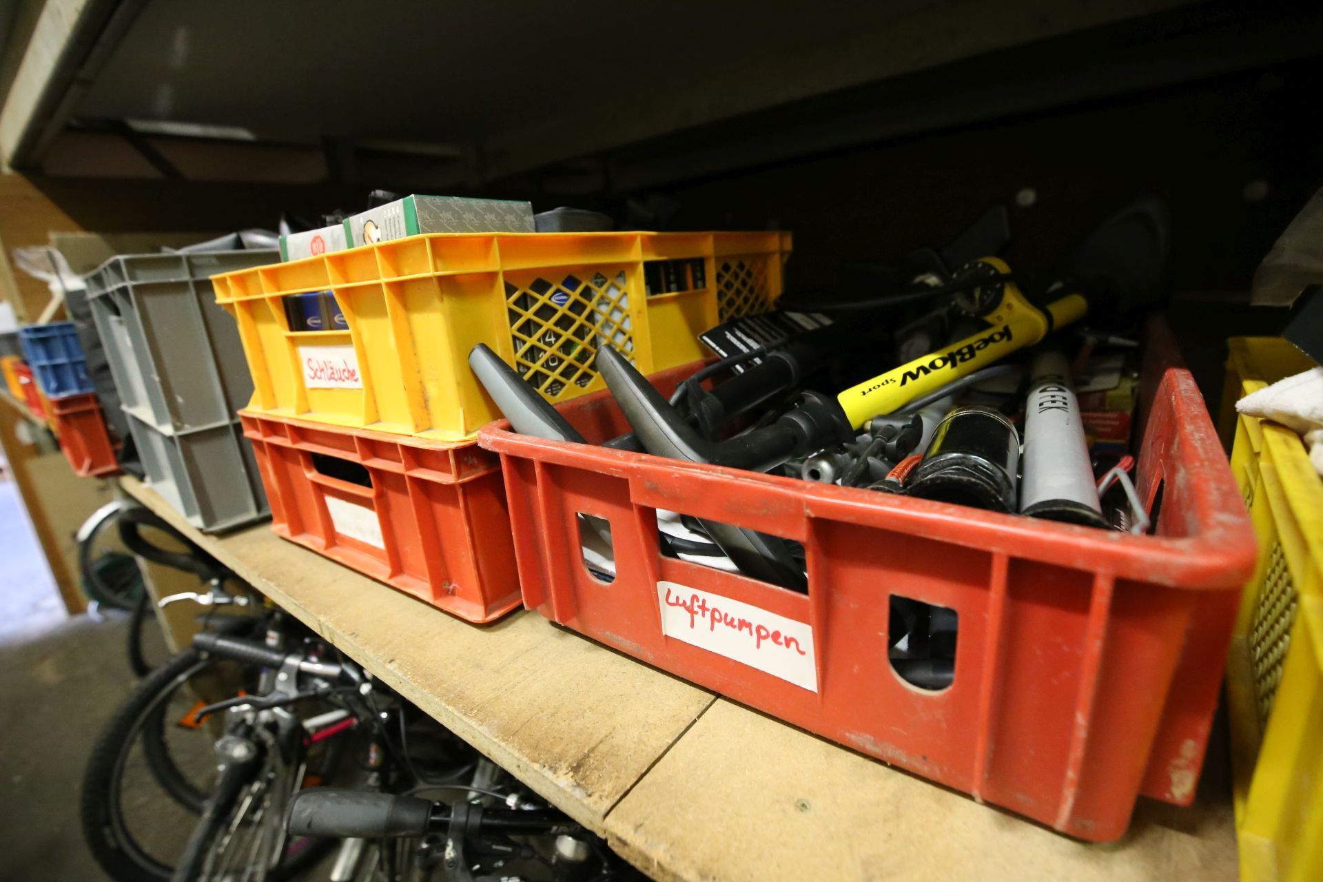 Rote und gelbe Plastikkörbe mit Luftpumpen und anderem Fahrradzubehör.