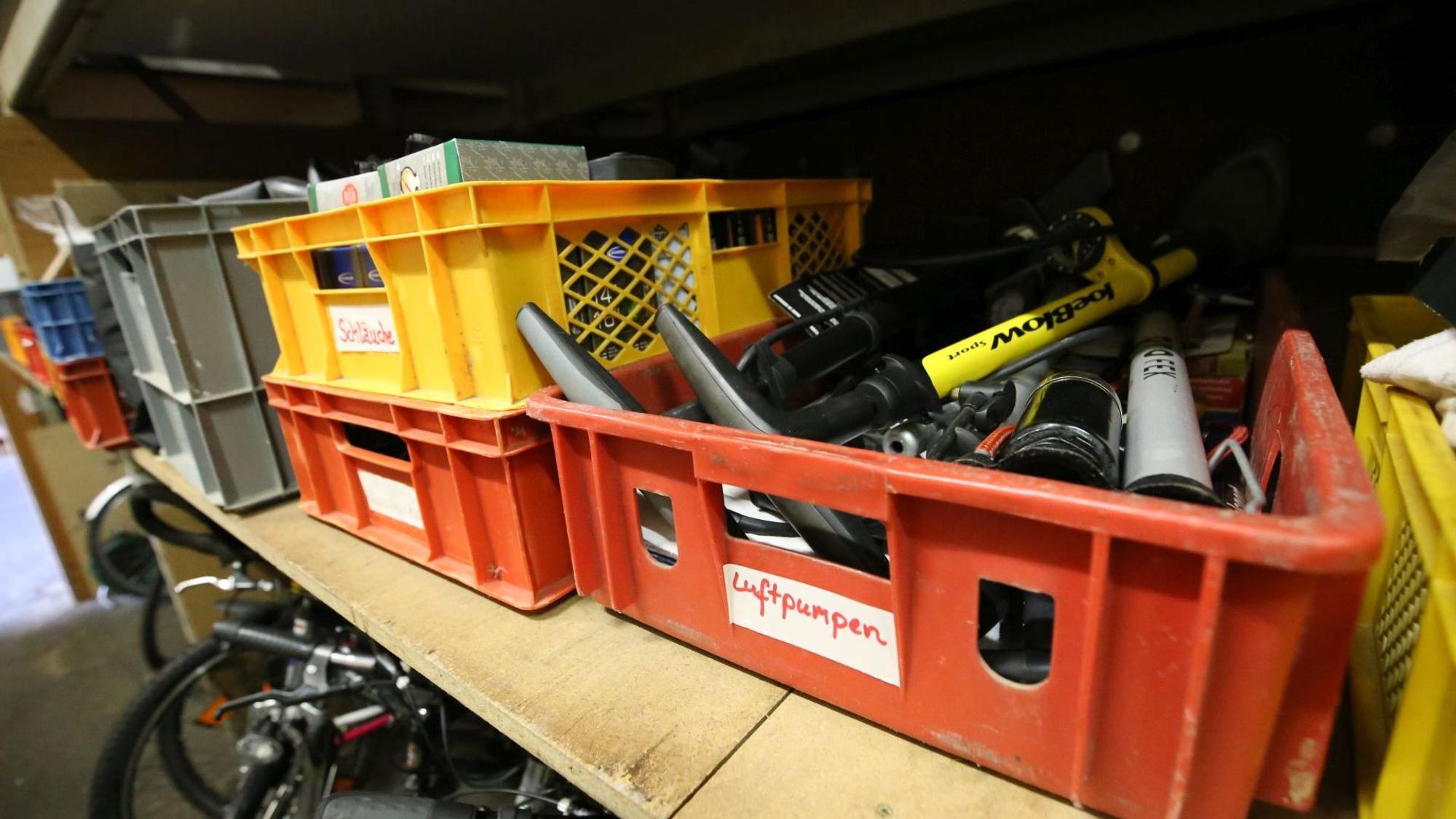 Rote und gelbe Plastikkörbe mit Luftpumpen und anderem Fahrradzubehör.
