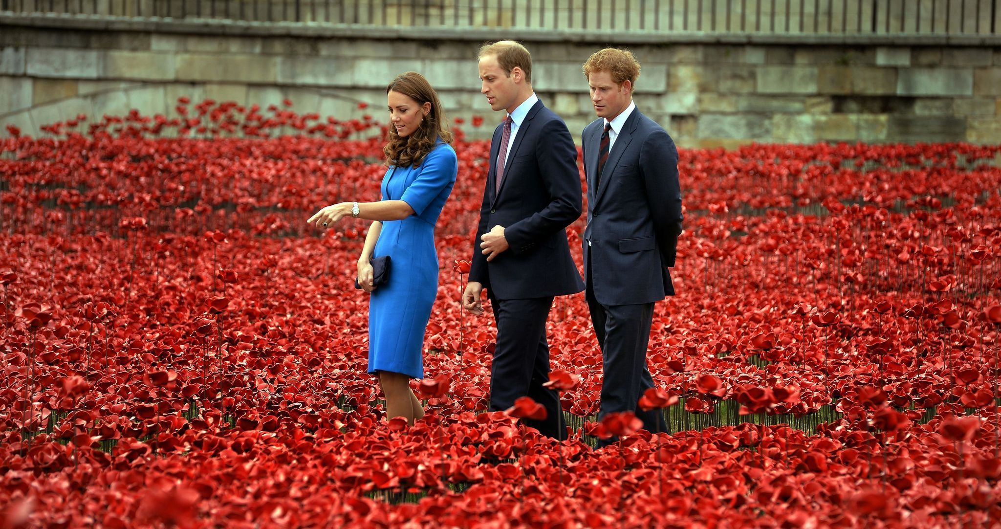 Kate, Prinz William und Prinz Harry stehen in roten Poppys.