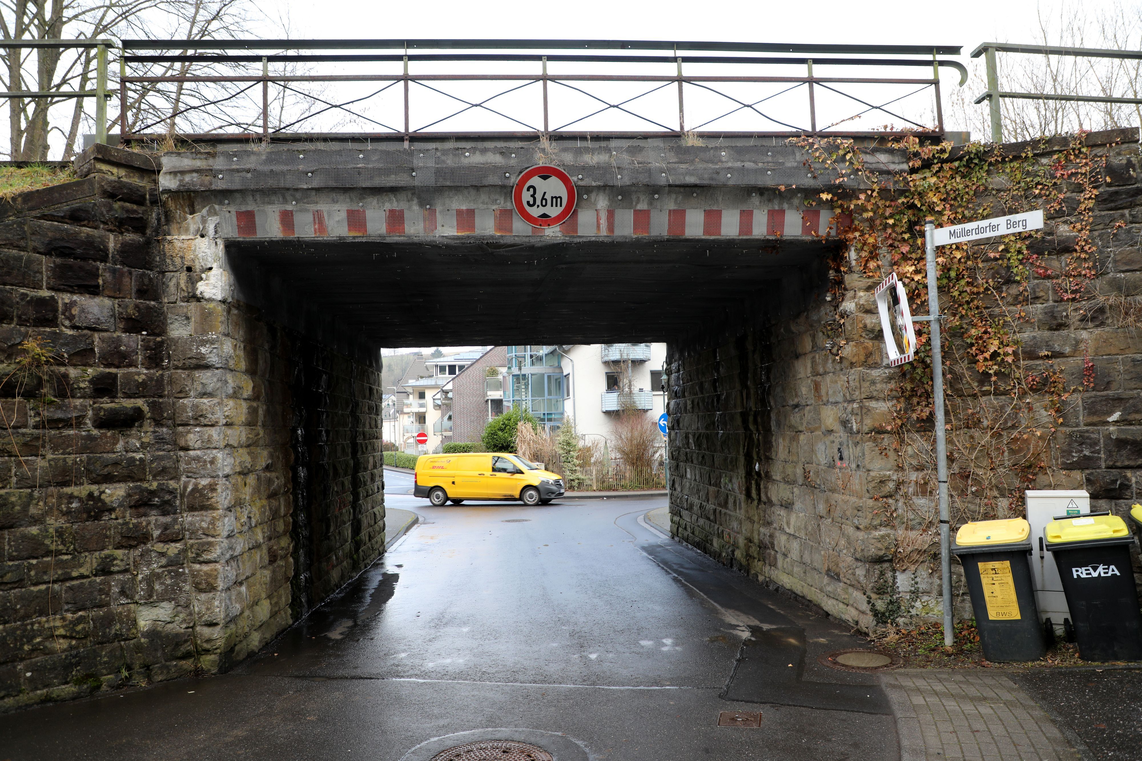 Eine enge Durchfahrt mit nasser Straße, am Ende der Durchfahrt ein Postauto