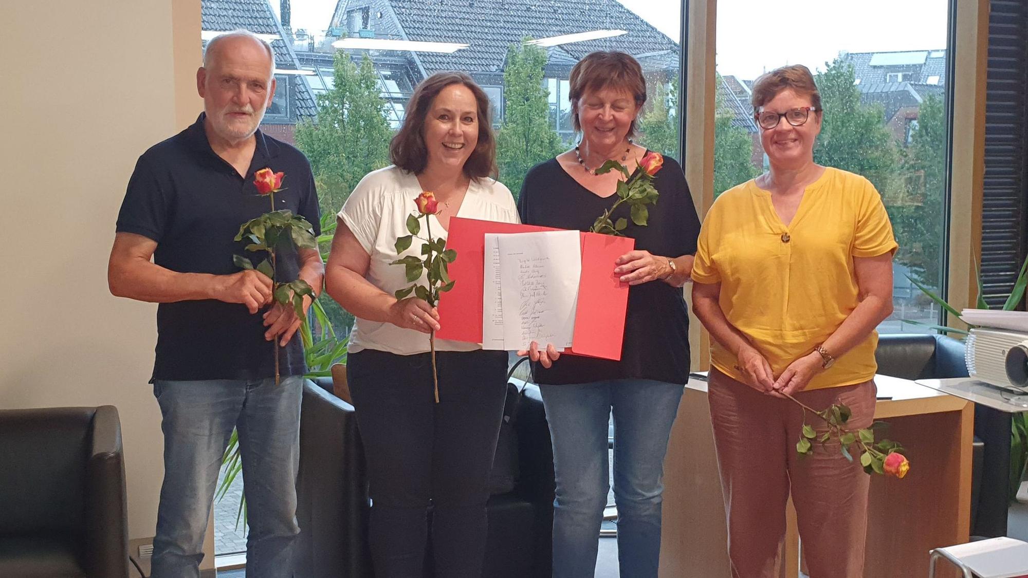 Drei Frauen und ein Mann lächeln in die Kamera.