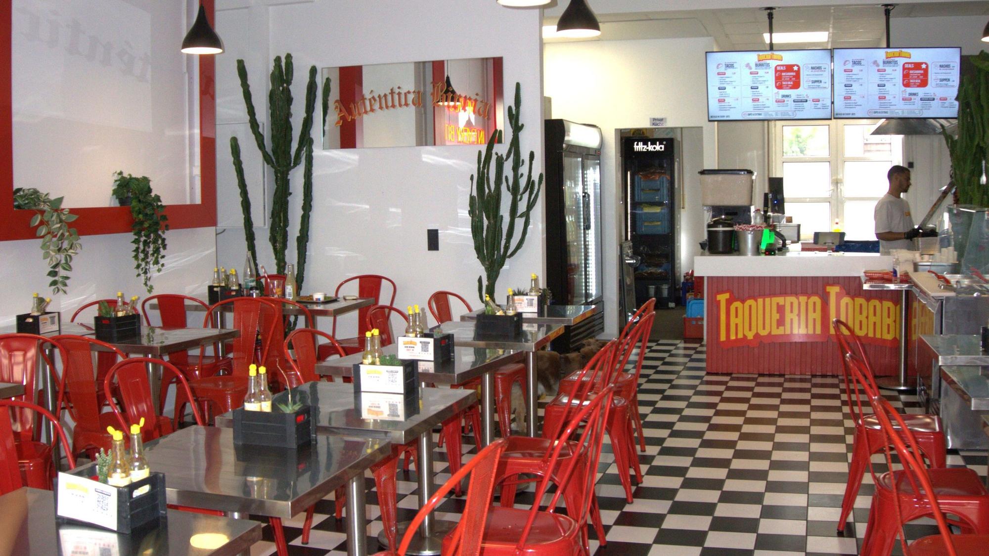 Die Taqueria Tobabo von innen mit roten Stühlen und silbernen Tischen.