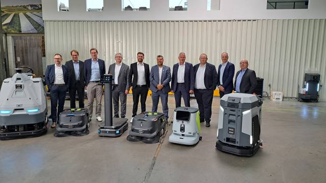 Das Foto zeigt eine Gruppe von Männern und davor einige Roboter.