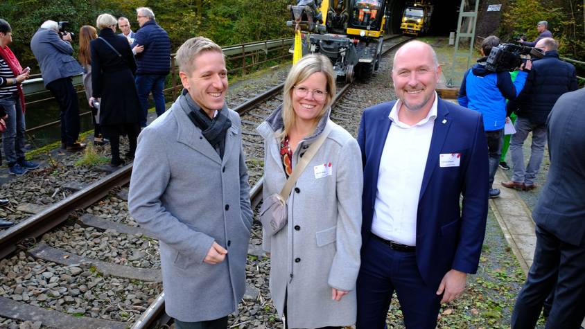 Die Landräte und der heutige ADD-Chef stehen neben einer Eisenbahntrasse.