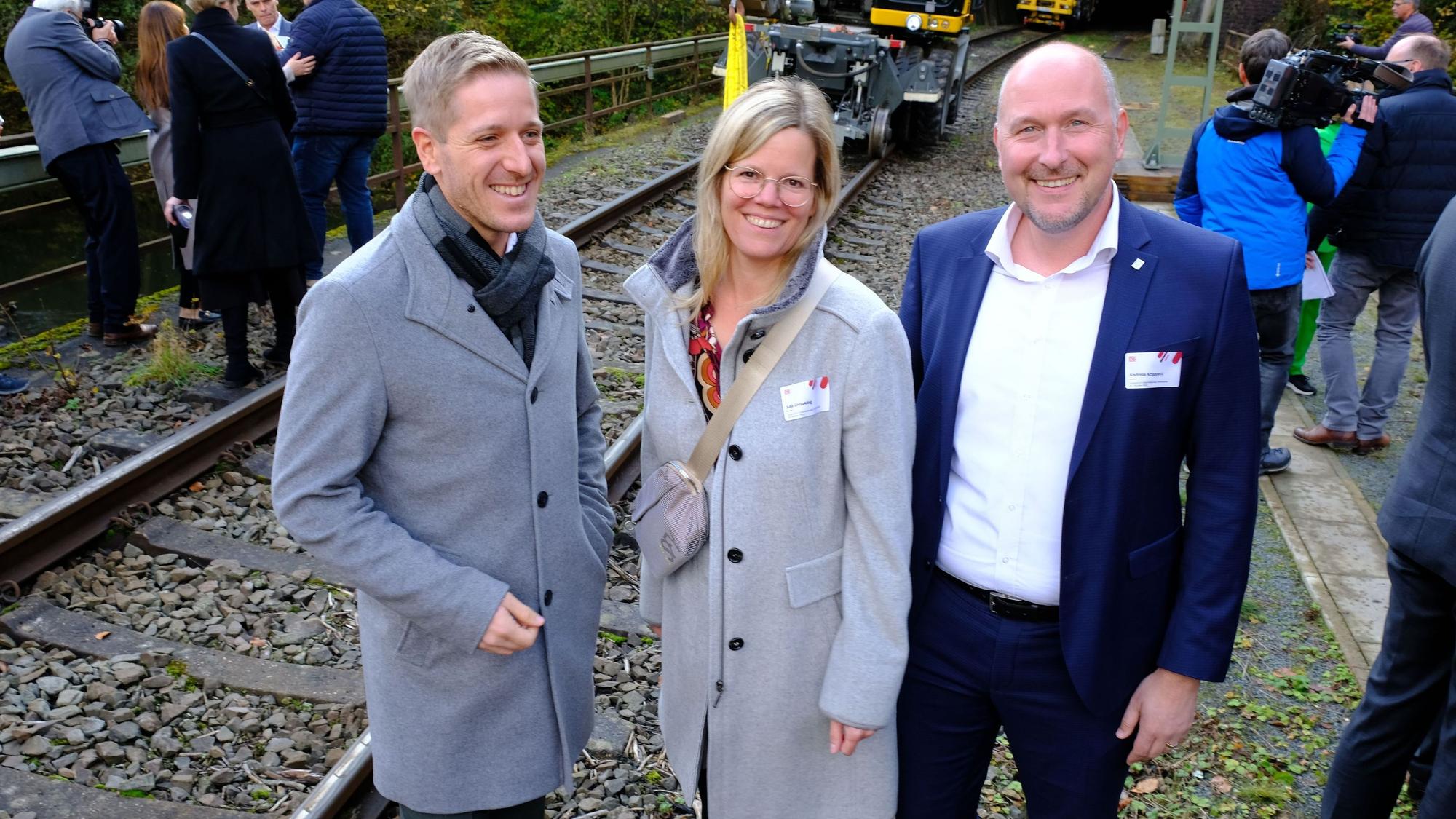 Die Landräte und der heutige ADD-Chef stehen neben einer Eisenbahntrasse.