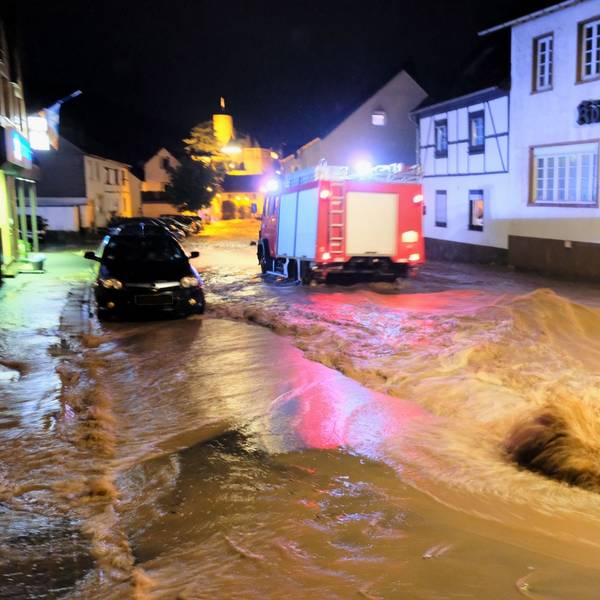 Über die Hengebachstraße schoss die Flut im Juli 2021 in die Heimbacher Innenstadt. Ein Feuerwehrfahrzeug fährt durch das Wasser.