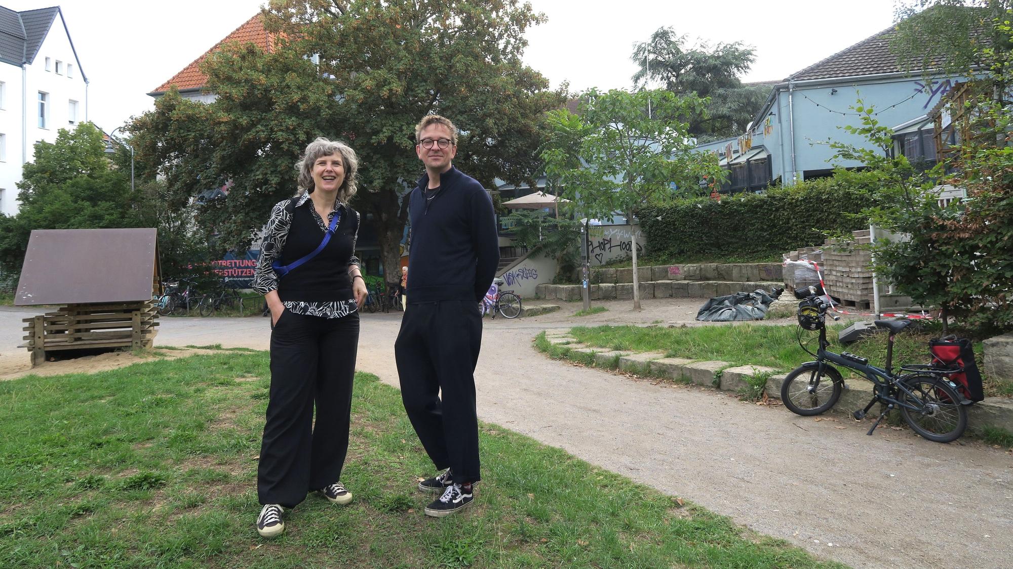 Eine Frau und ein Mann stehen nebeneinander in einem Park vor dem Bürgerzentrum Ehrenfeld.