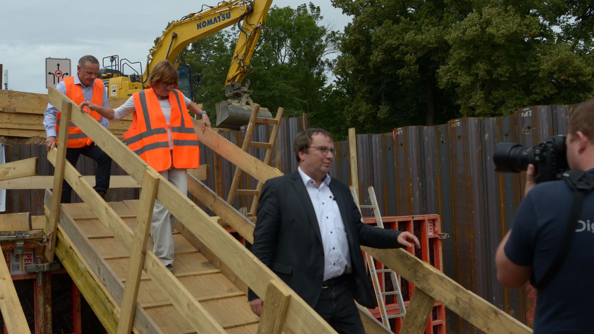 Krischer geht auf der Baustelle über eine Holzbrücke.