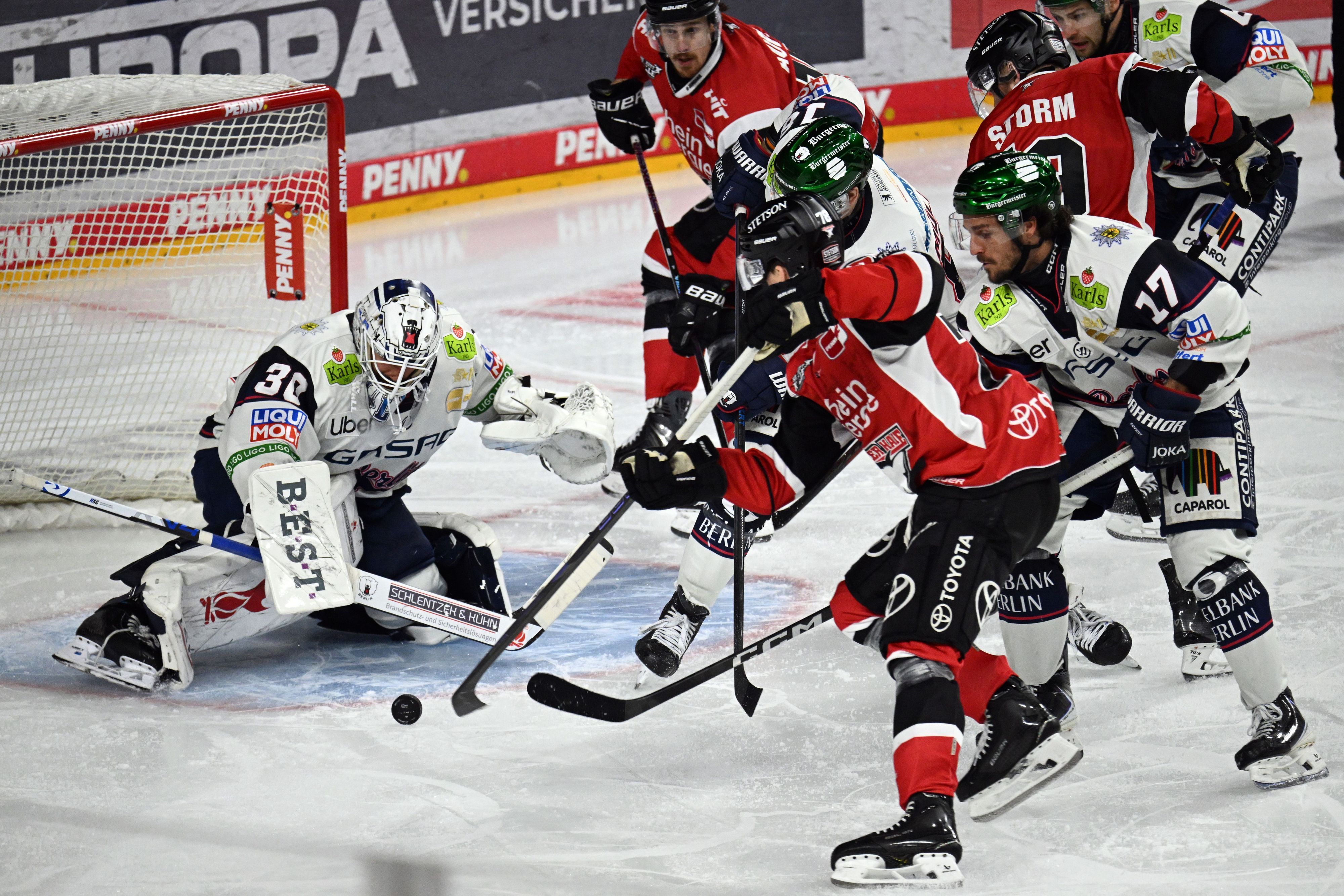 Dominik Bokk (Kölner Haie) und Torwart Jake Hildebrand (Eisbären Berlin) kämpfen auf dem Eis um den Puck.