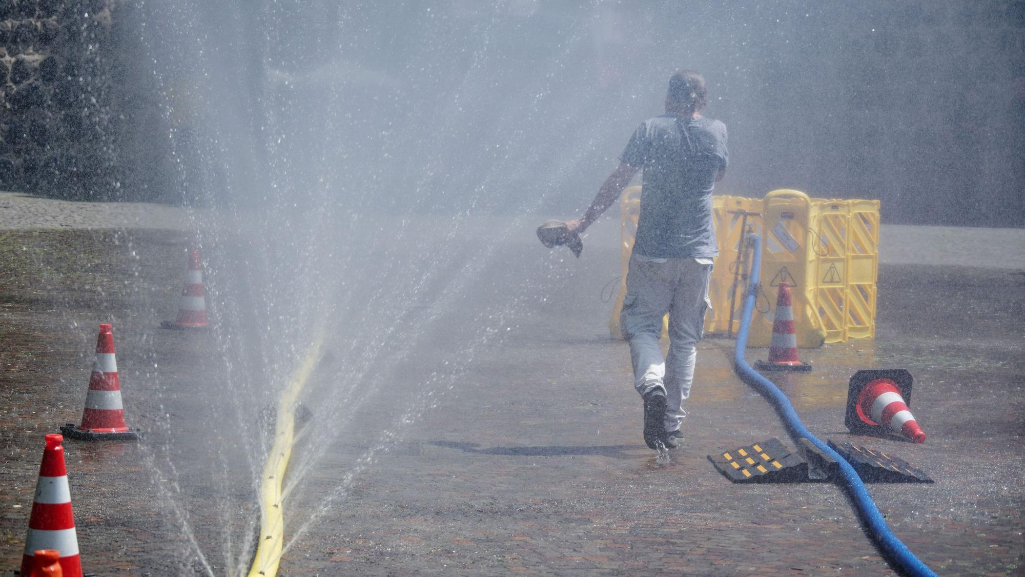 Köln: Passanten genießen Wasserfontänen, die im Rahmen der Hitzeaktion „Cooling Cologne“ der Stadt Köln im Juni dieses Jahres auf dem Rudolfplatz in der Innenstadt installiert wurden.