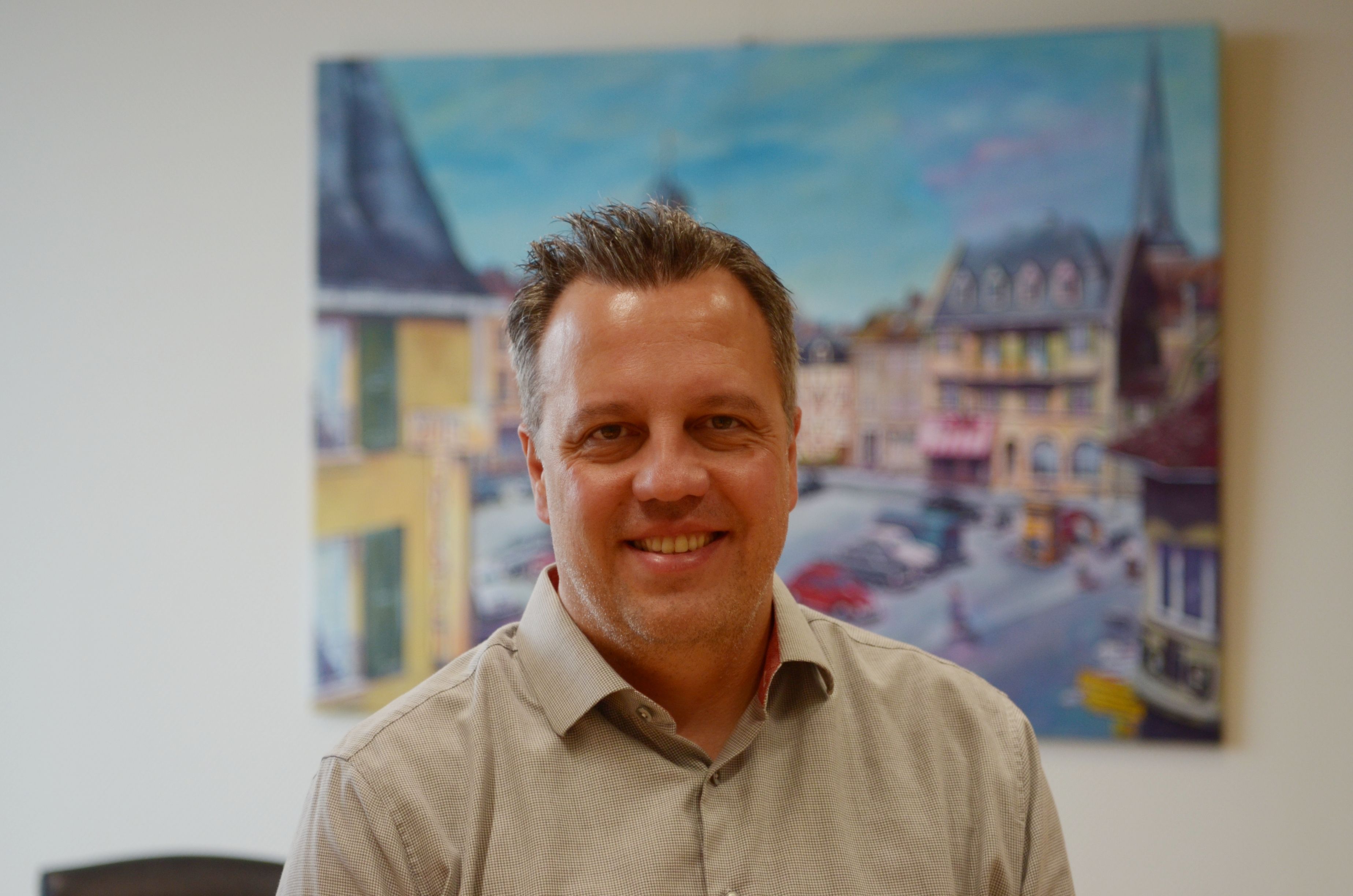 Das Bild zeigt Reichelt vor einem Gemälde in seinem Büro.