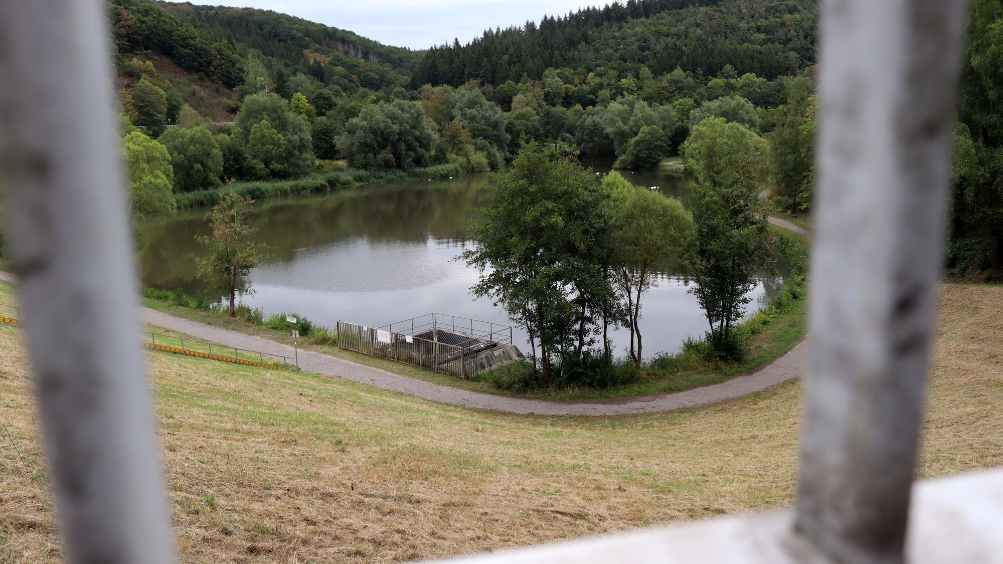 Hinter Gitterstäben ist das Hochwasserrückhaltebecken in Eicherscheid zu sehen.