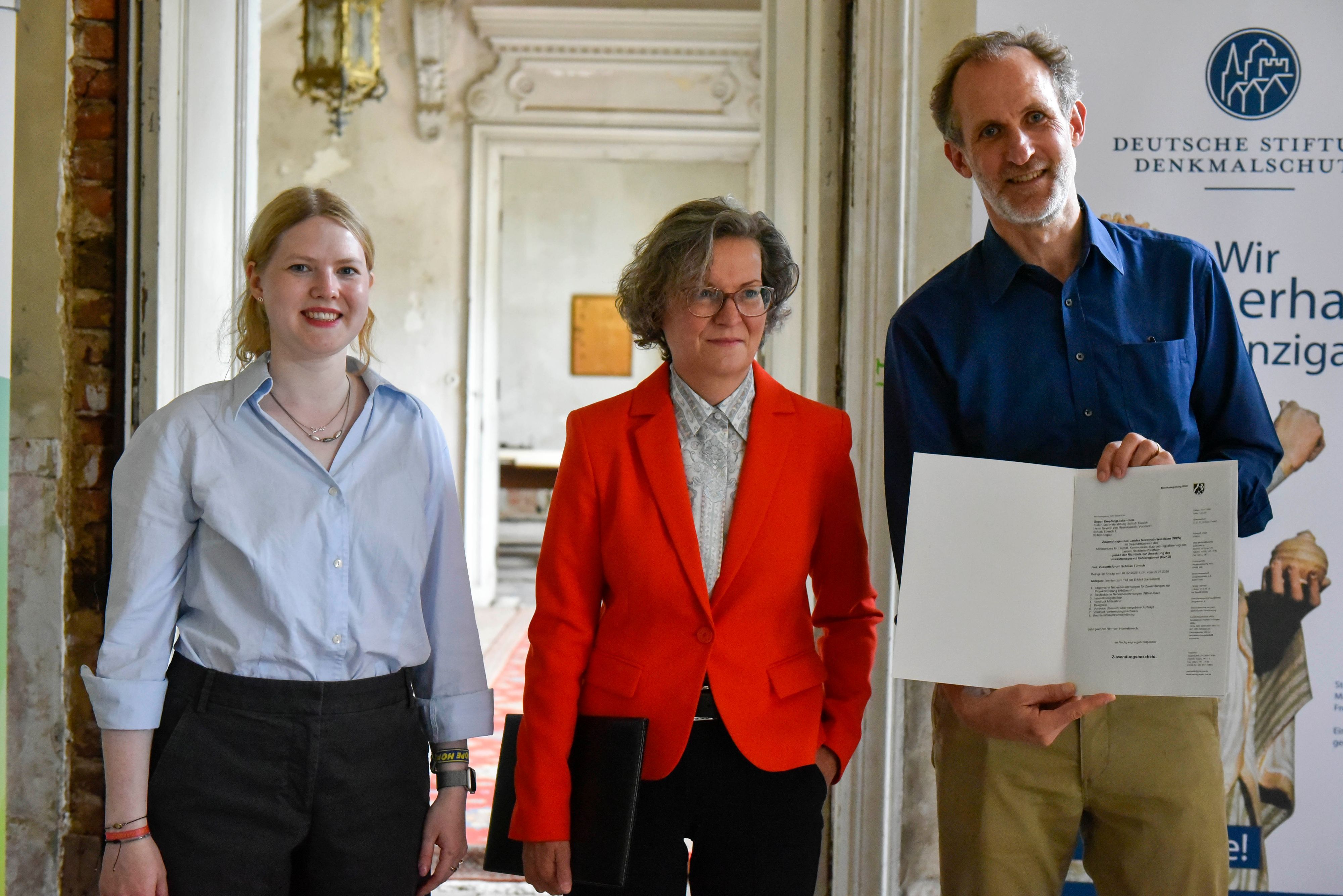 Ministerin Ina Scharrenbach (Mitte) übergab den Fördermittelbescheid über rund 27 Millionen Euro an den Vorstand der Kultur- und Naturstiftung Schloss Türnich Graf Severin von Hoensbroech und Lovis Schaeffer.