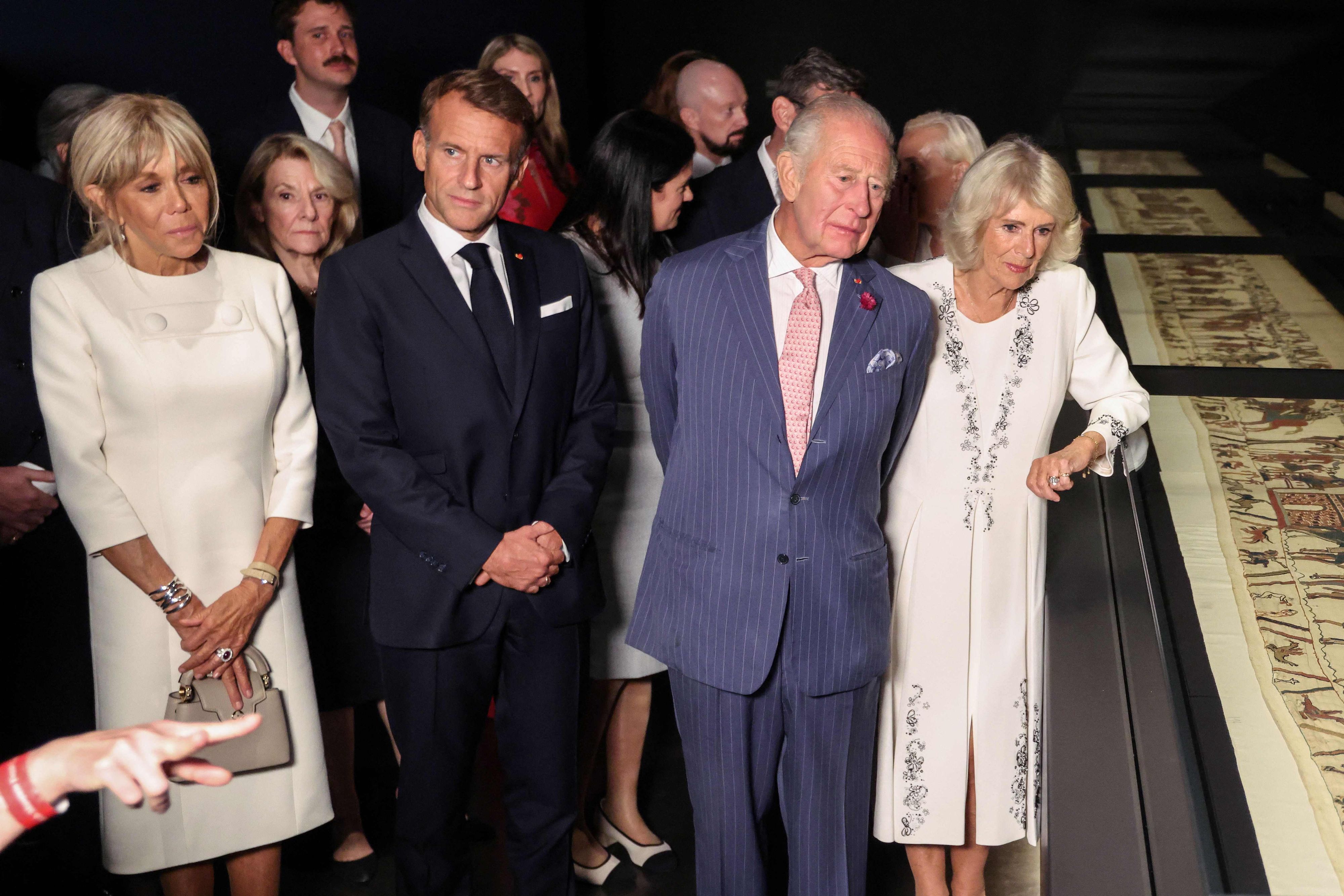 Emmanuel Macron, König Charles III. und Königin Camilla betrachten bei einer Vorbesichtigung im British Museum Teile des historischen Teppichs von Bayeux.
