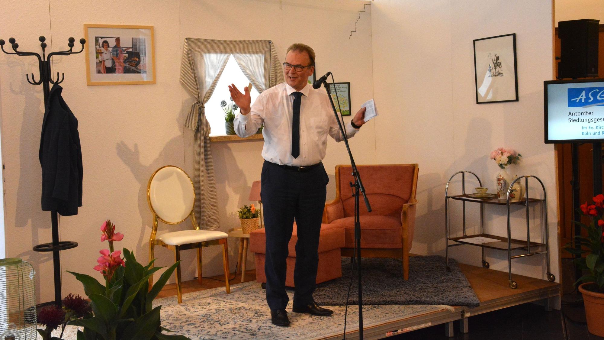 Ein Mann steht auf einer improvisierten Bühne und spricht in ein Mikrofon.
