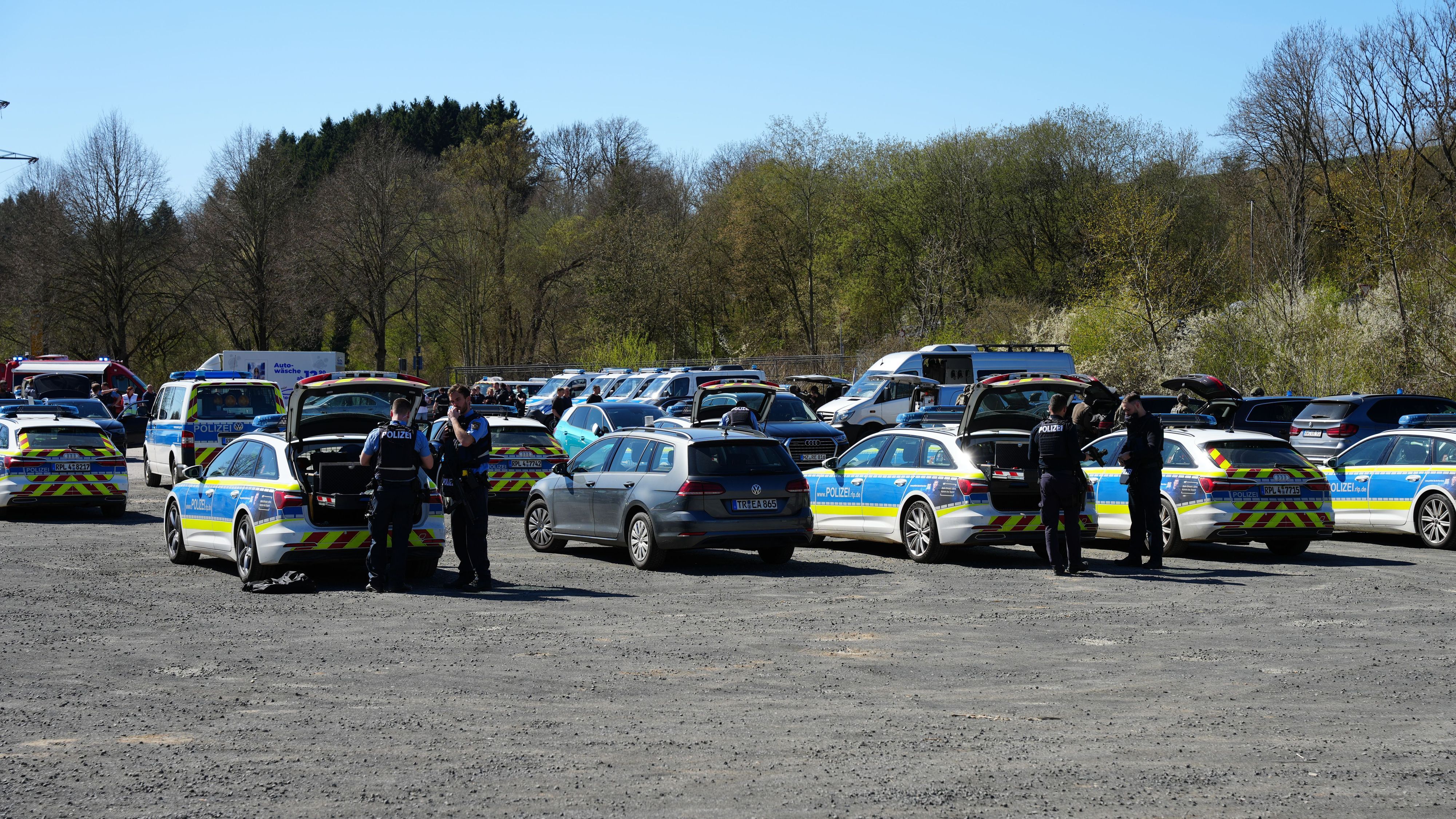 Polizisten stehen an ihren Fahrzeugen und bereiten sich in Prüm auf ihren Einsatz vor.