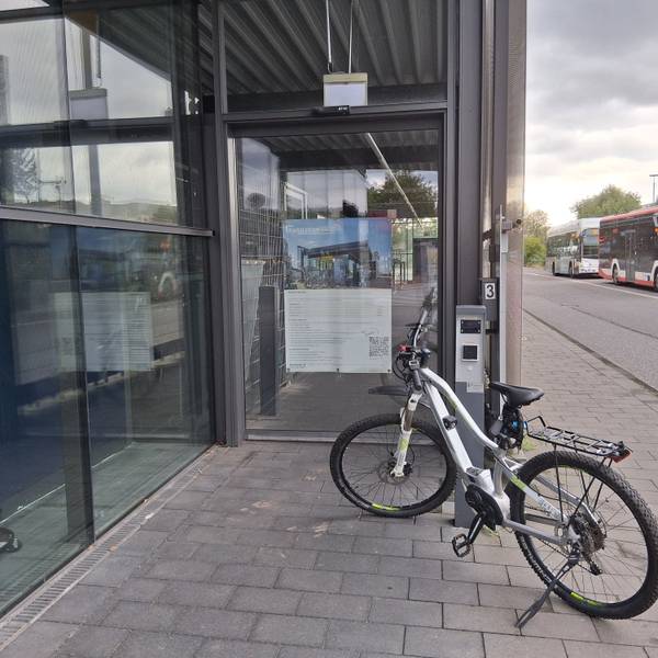 ein Fahrrad steht vor einer verschlossenen Glastür, an der ein Chiplesegerät angebracht ist