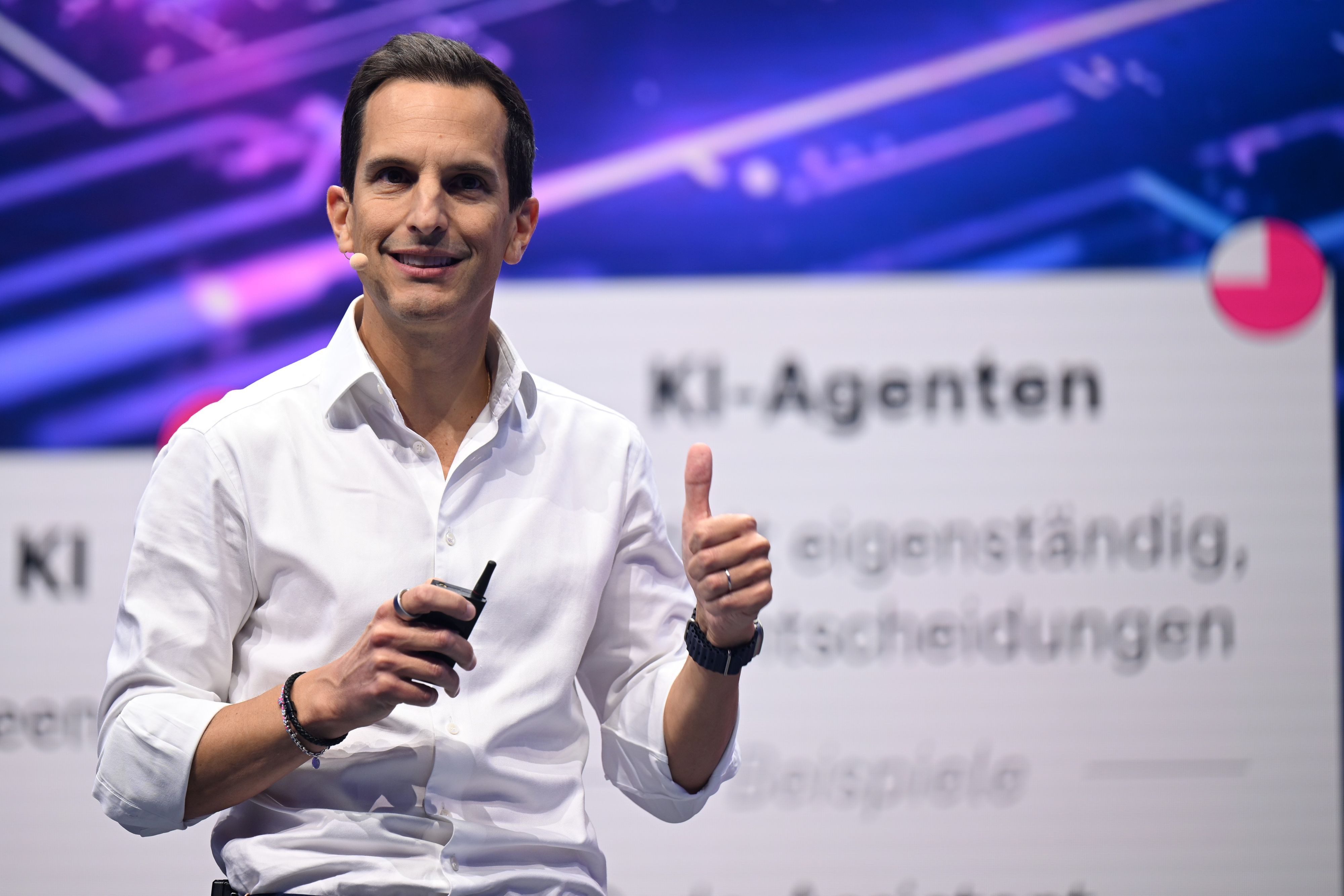 Rodrigo Diehl, steht im weißen Hemd und ohne Krawatte auf der Digitalmesse Digital X 2025 lächelnd auf einer Bühne und spricht zum Publikum