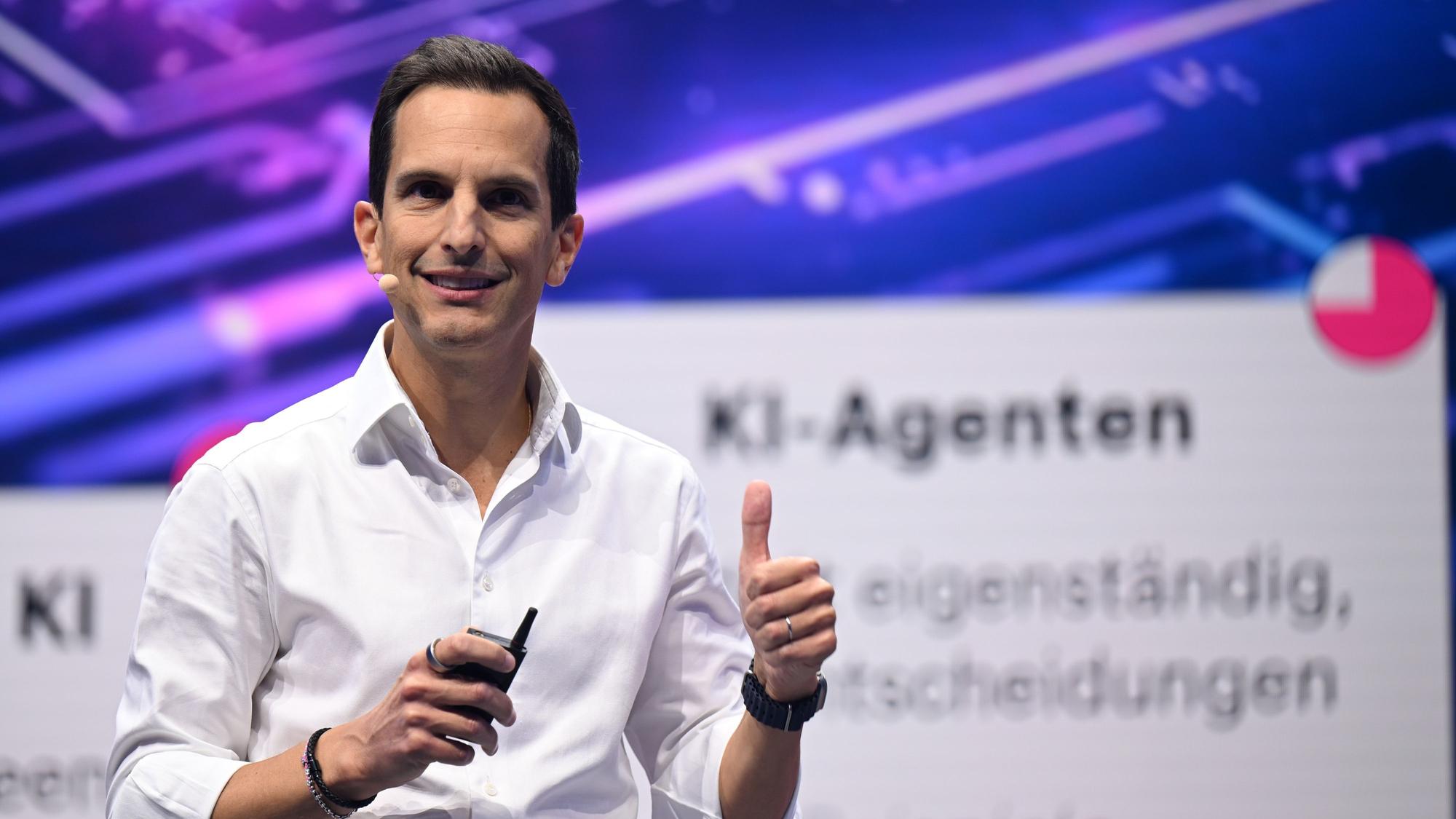 Rodrigo Diehl, steht im weißen Hemd und ohne Krawatte auf der Digitalmesse Digital X 2025 lächelnd auf einer Bühne und spricht zum Publikum