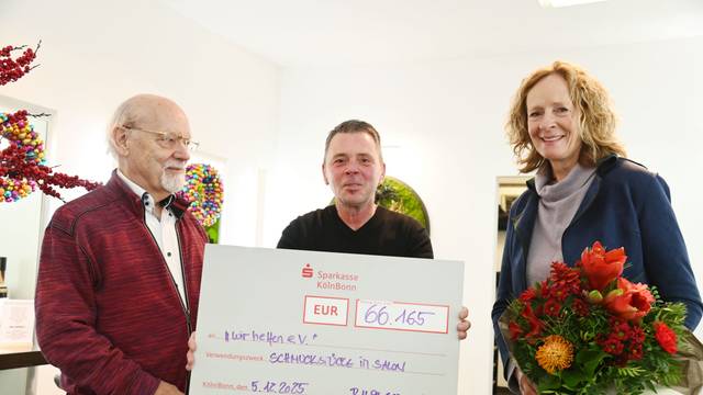 Der Goldschmiedemeister Herbert Schmelzer und Friseurmeister Ralph Schwalbach überreichen Isabella Neven DuMont von wir helfen e.V. einen symbolischen Scheck in Höhe von 66.165 Euro
