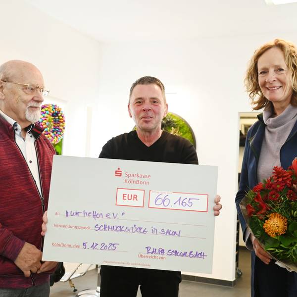 Der Goldschmiedemeister Herbert Schmelzer und Friseurmeister Ralph Schwalbach überreichen Isabella Neven DuMont von wir helfen e.V. einen symbolischen Scheck in Höhe von 66.165 Euro