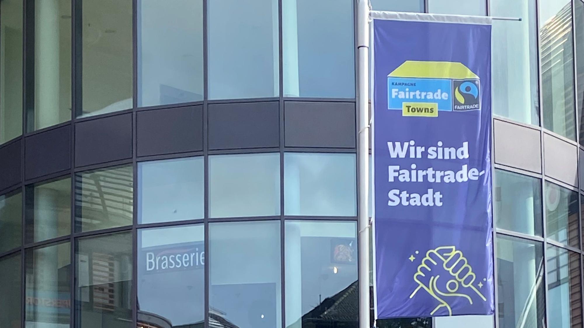 Die Fair-Trade-Fahne wird zur Aktionswoche vor dem Rathaus gehisst.