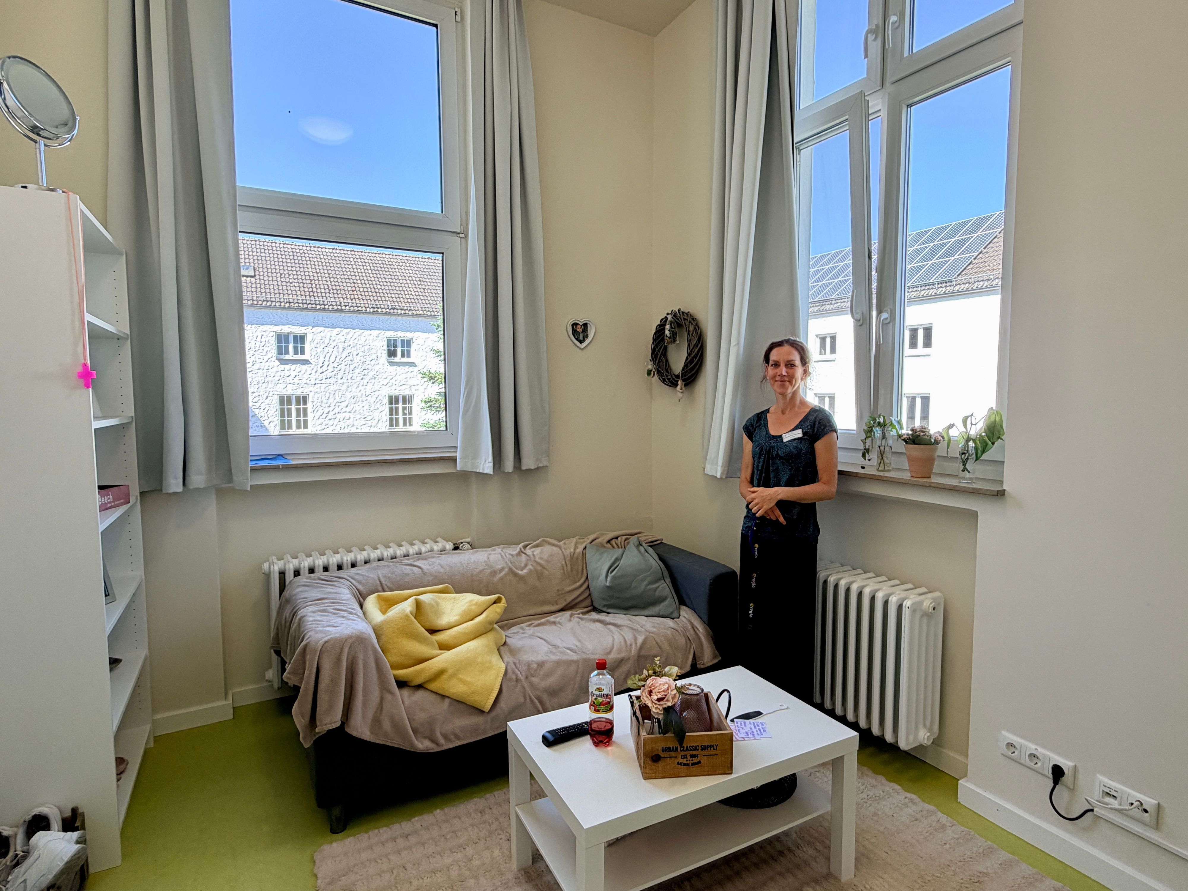 Das Bild zeigt einen Blick in ein Bewohnerzimmer. Zu sehen sind ein Sofa, ein Tisch und ein Regal.