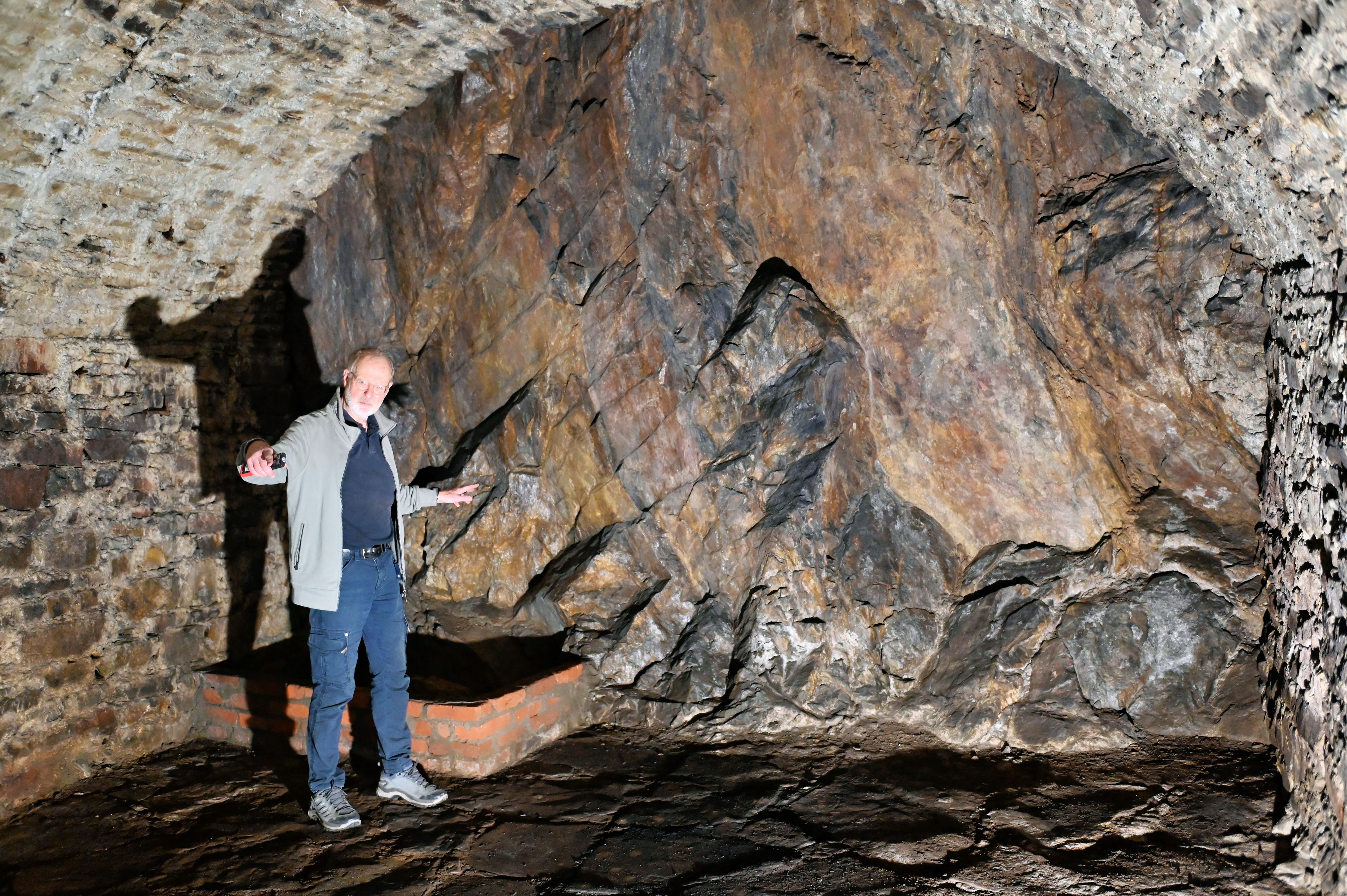 Norbert Liebing steht im alten Felsenkeller in Bad Münstereifel und hat die Arme ausgebreitet.