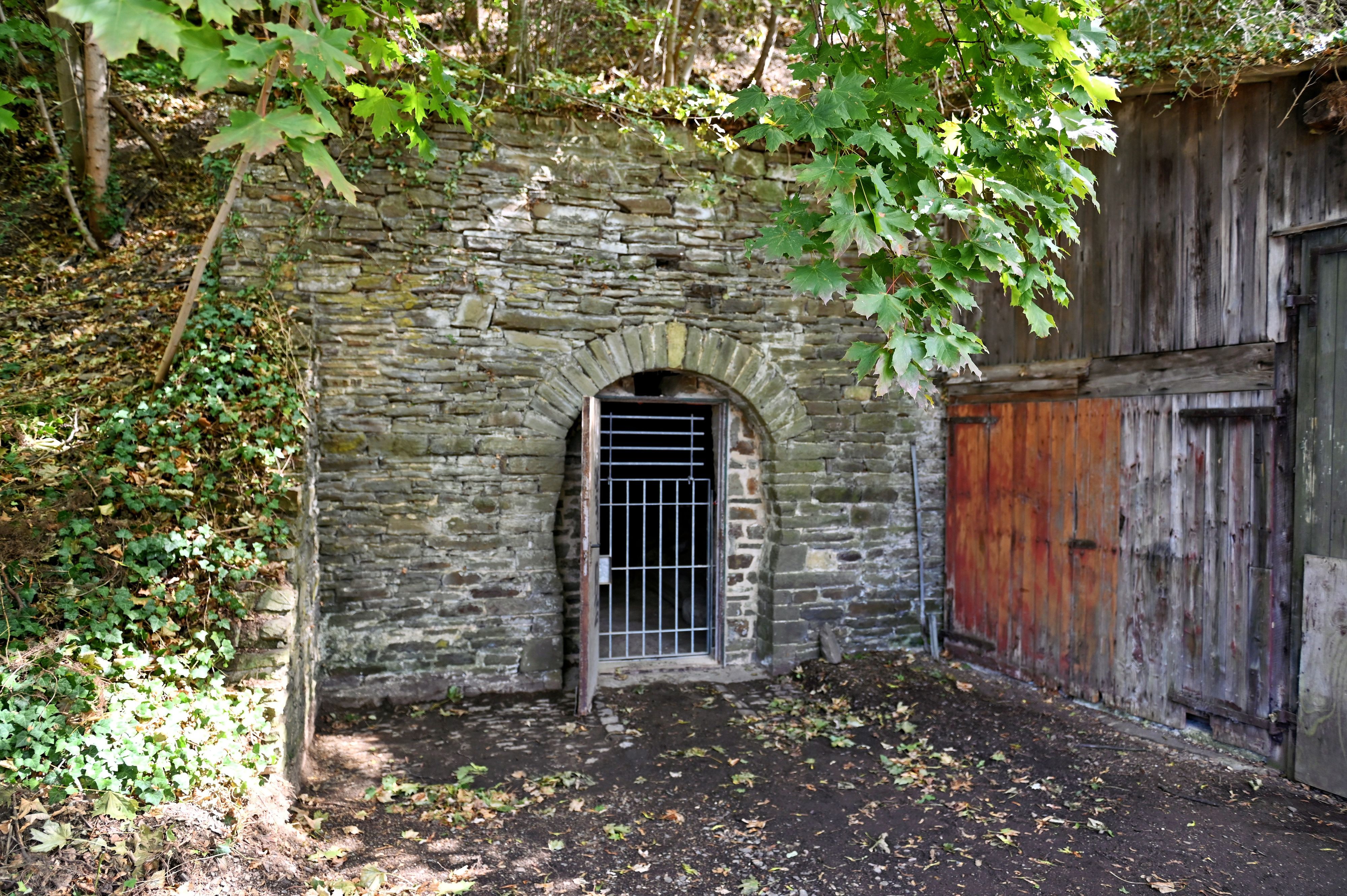 In einer Bruchsteinmauer ist eine Gittertür, die in den Felsenkeller von Bad Münstereifel führt.