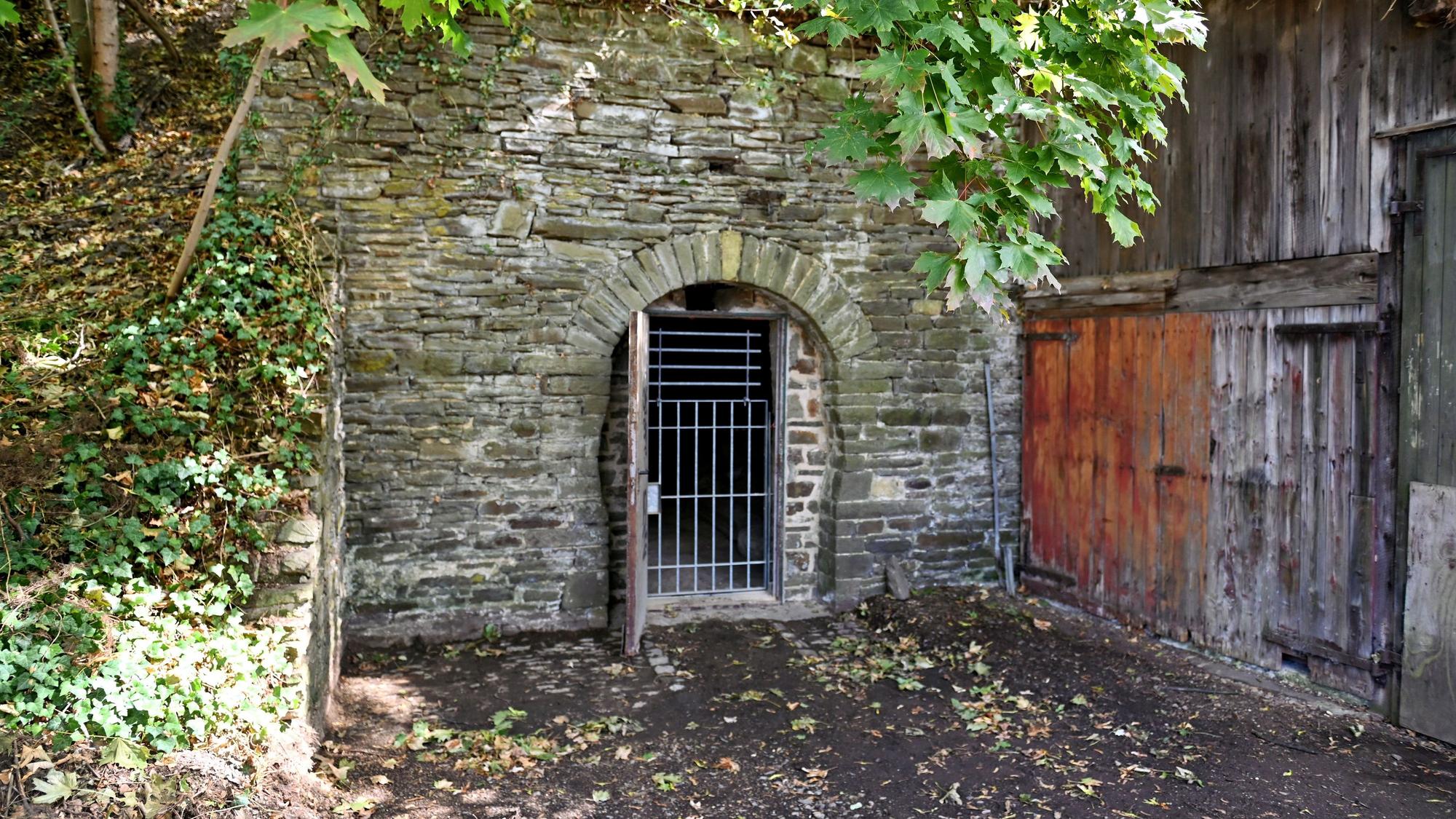 In einer Bruchsteinmauer ist eine Gittertür, die in den Felsenkeller von Bad Münstereifel führt.