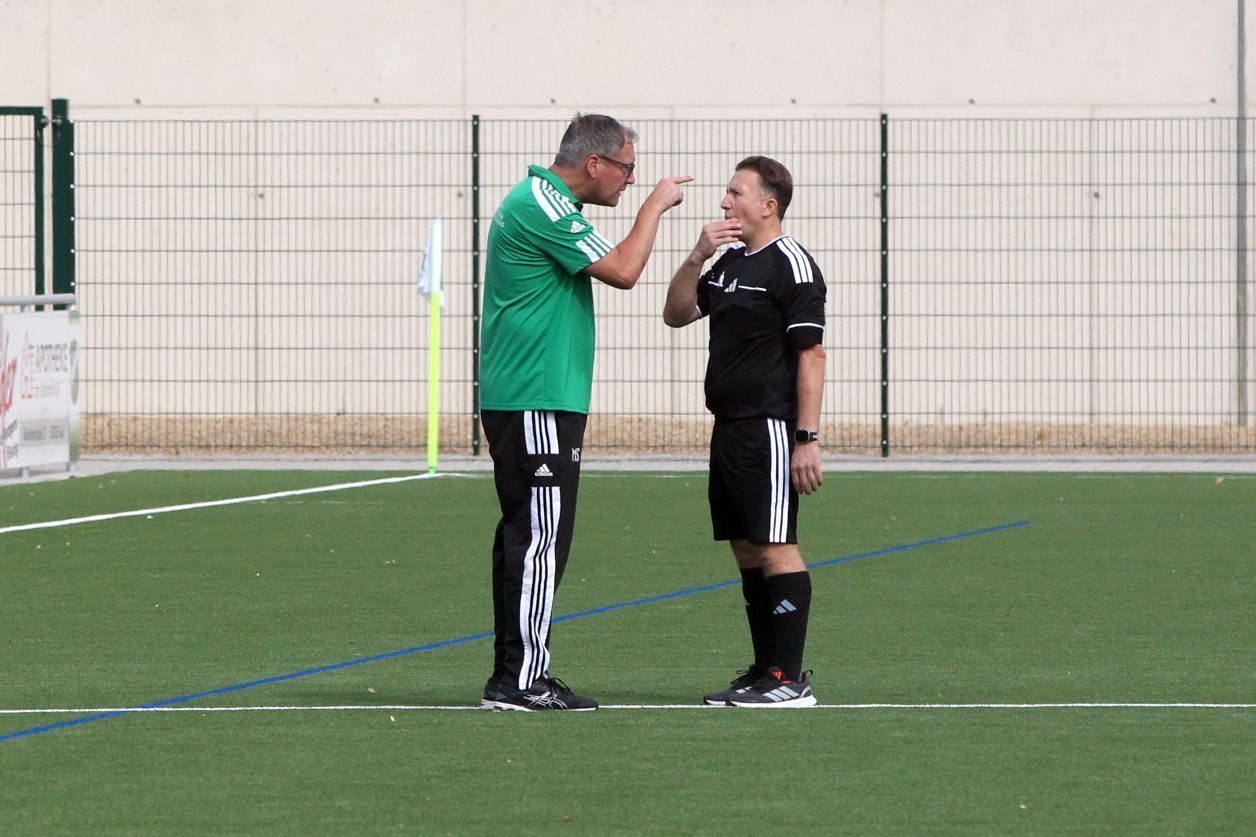 Sötenichs Trainer Markus Sabel diskutiert gestikulierend mit dem Schiedsrichter, der sich ins Gesicht fasst.