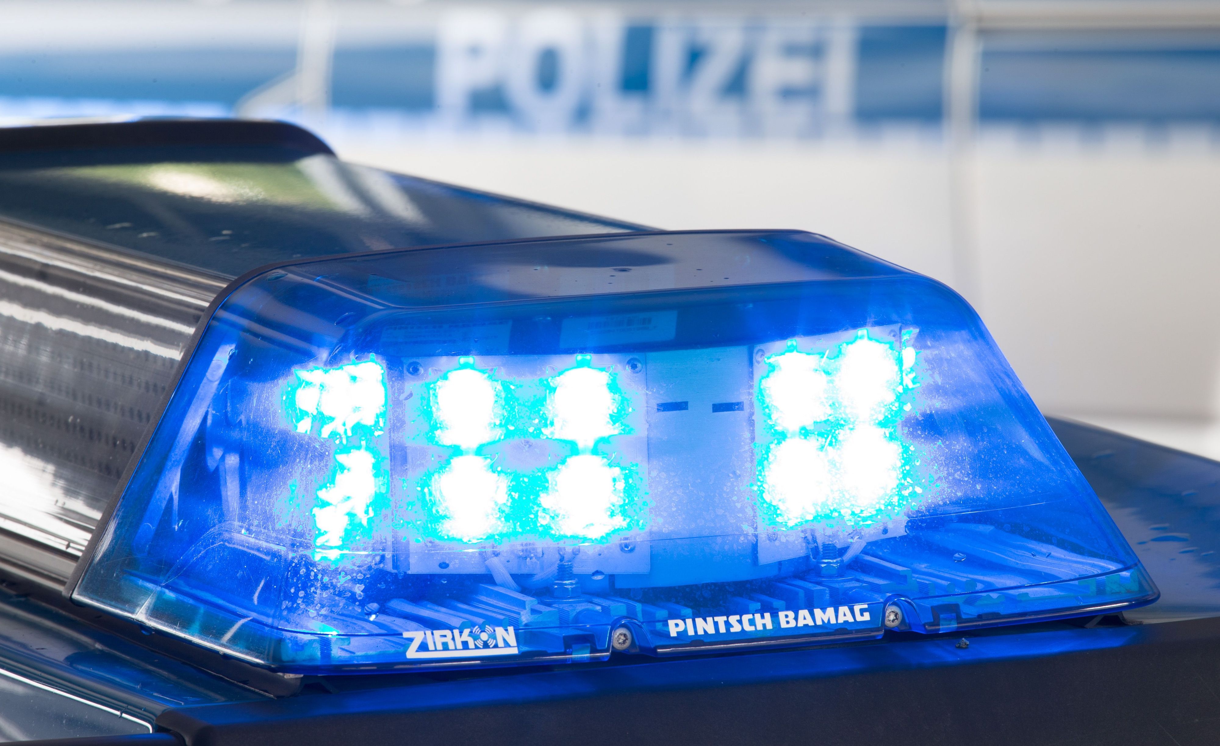 Das Foto zeigt ein Blaulicht auf dem Dach eines Einsatzfahrzeugs und ein zweites Polizeifahrzeug im Hintergrund.