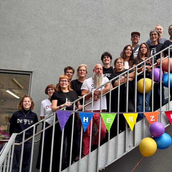 Viele Menschen stehen auf den Stufen einer Treppe. An der Treppe hängen Luftballons und eine Wimpelkette.