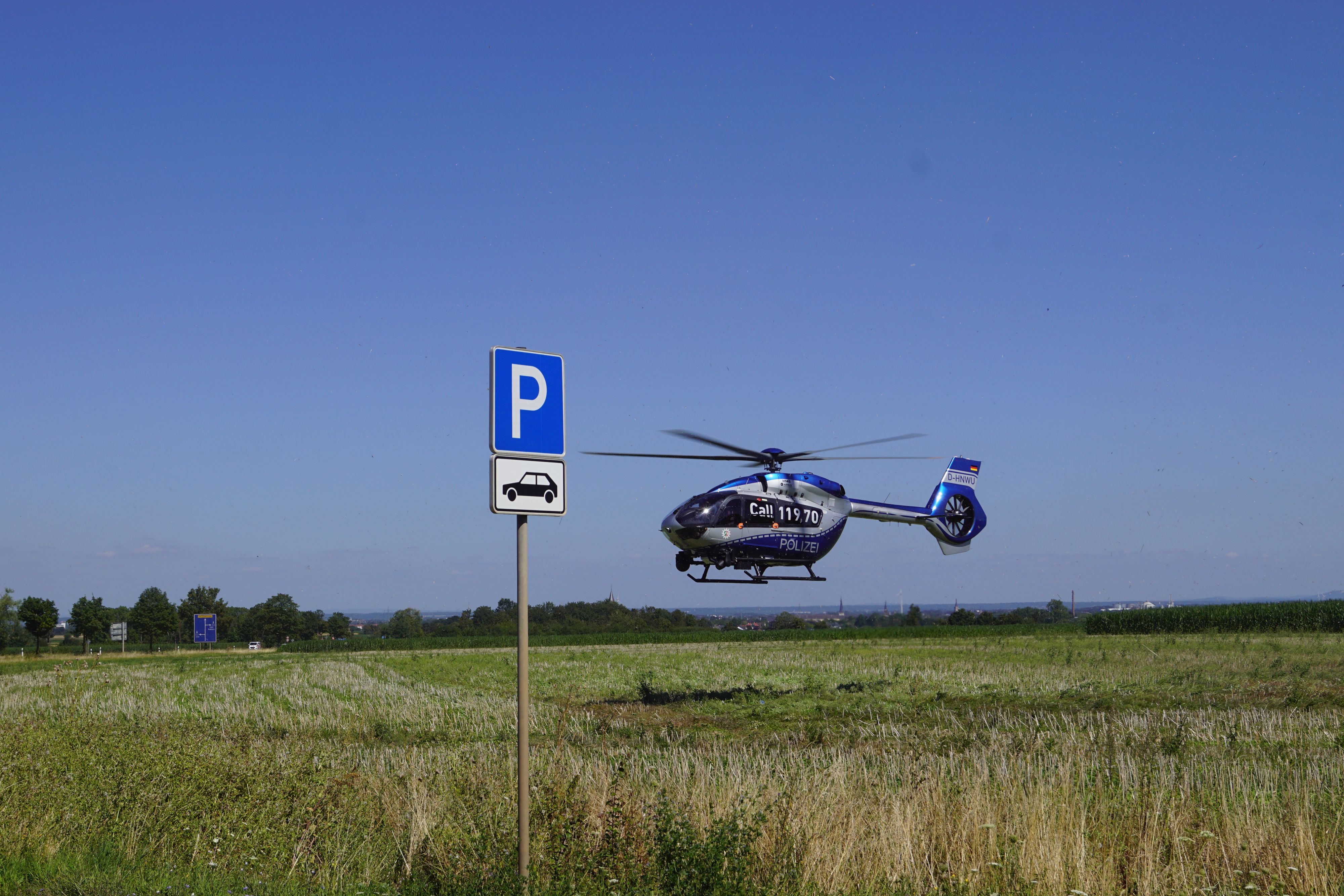 Ein Hubschrauber der Polizei landet auf einer Wiese.