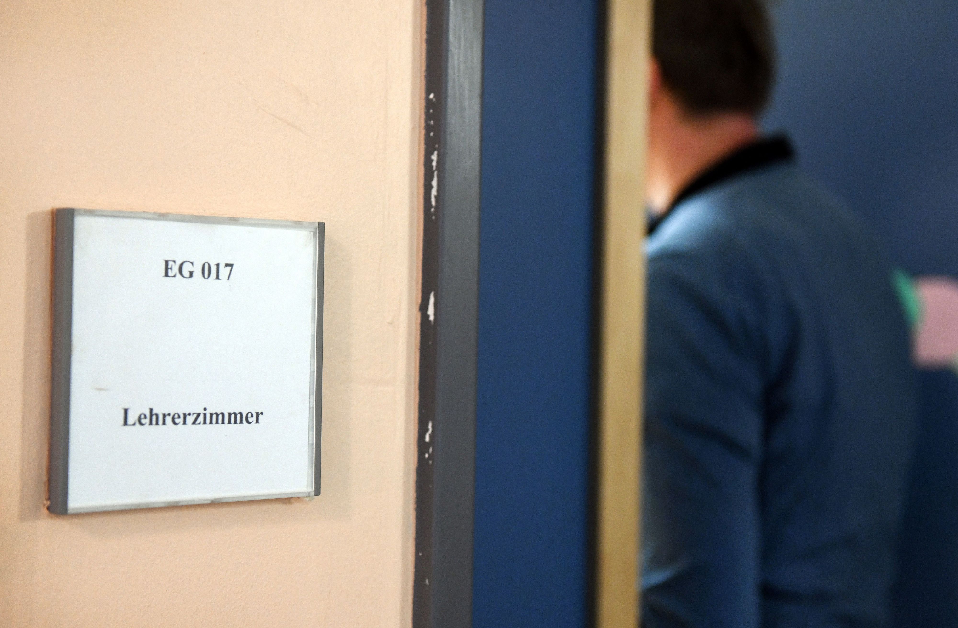 Ein Mann geht an einem Schild vorbei, das den Weg zum Lehrerzimmer weist. Lehrerinnen und Lehrer werden in NRW immer häufiger Opfer von Gewalt.