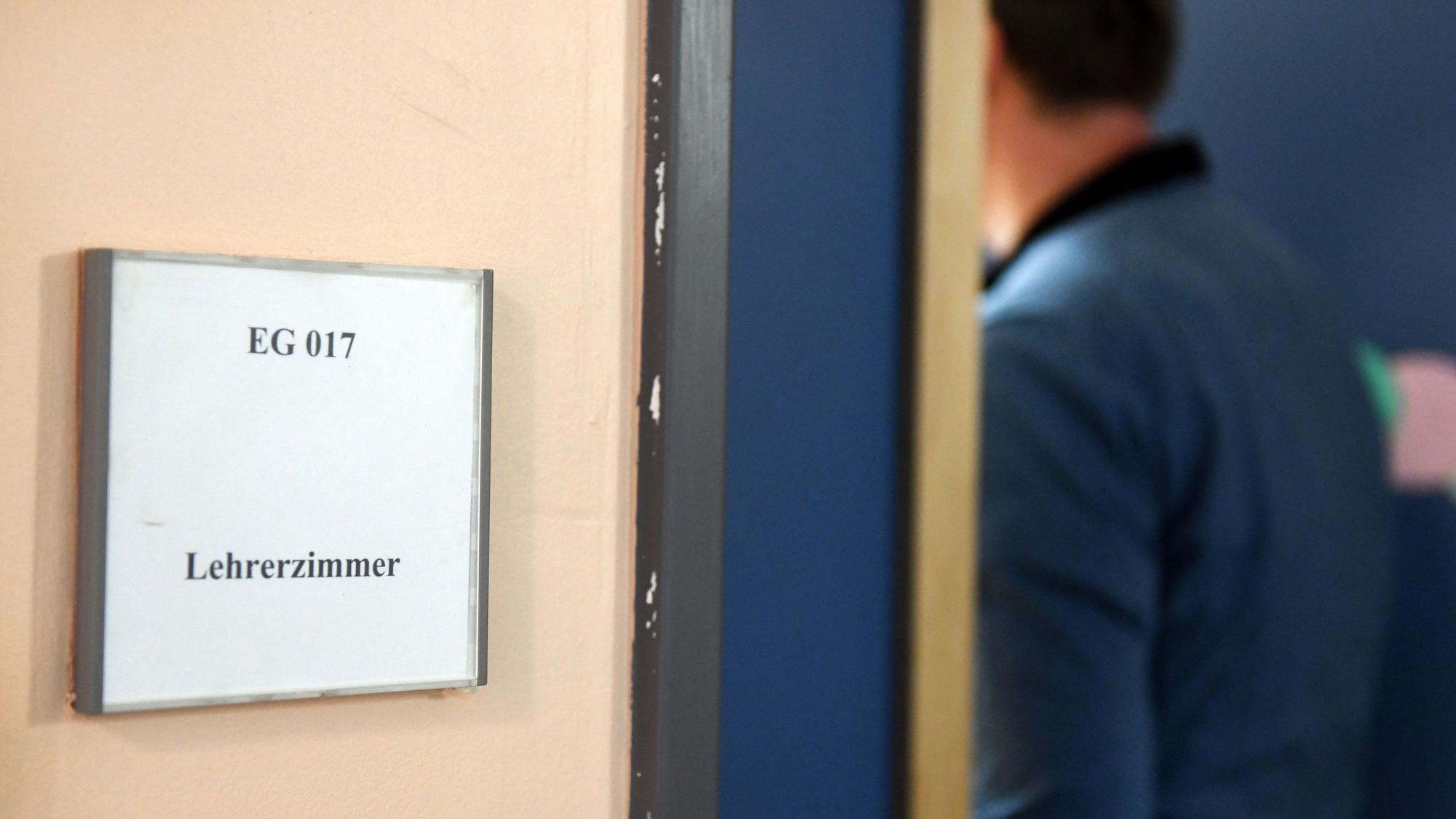 Ein Mann geht an einem Schild vorbei, das den Weg zum Lehrerzimmer weist. Lehrerinnen und Lehrer werden in NRW immer häufiger Opfer von Gewalt.