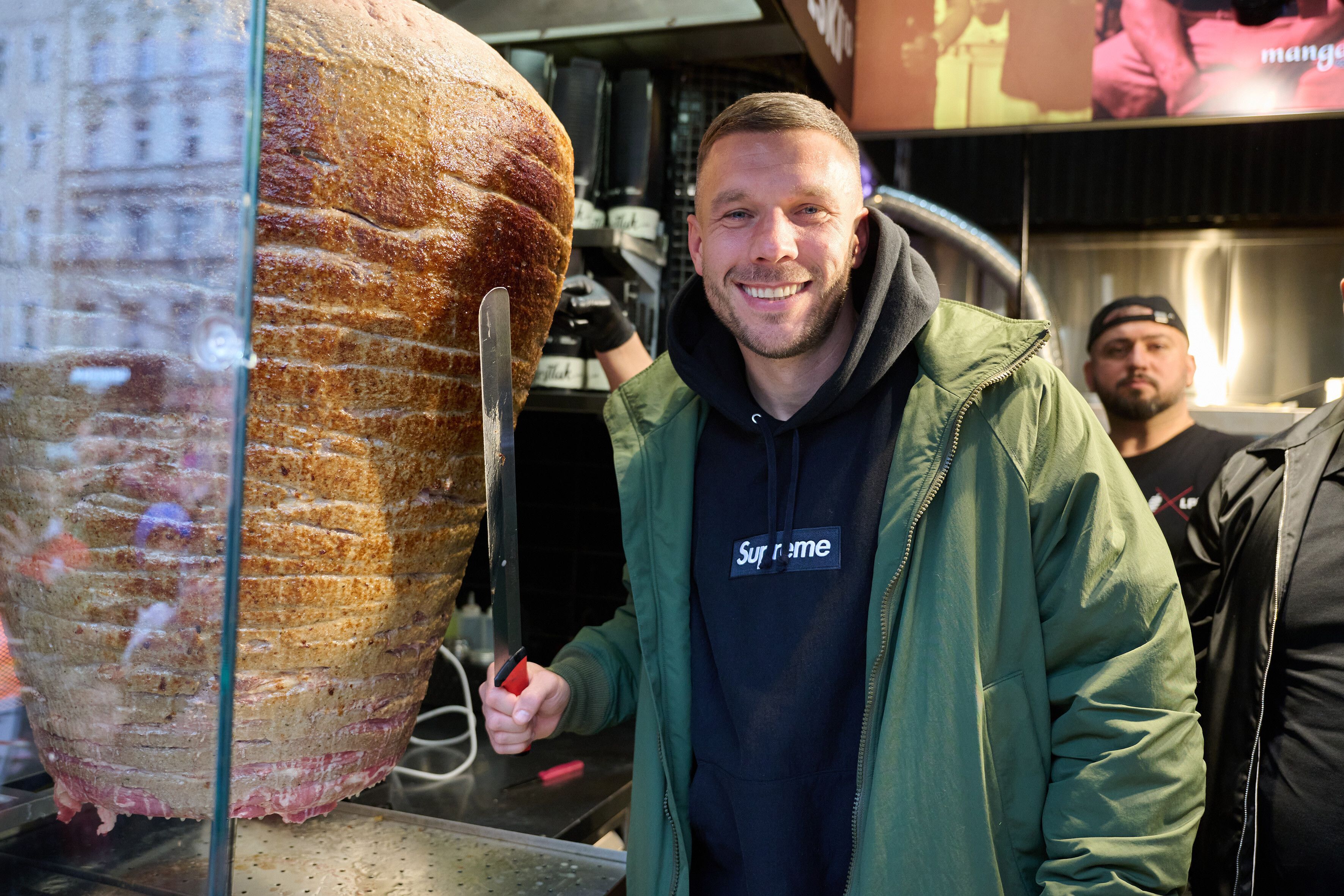 Lukas Podolski, ehemaliger Fußballprofi und Unternehmer, steht an einem Drehspieß während der Eröffnung eines „Mangal Döner“-Imbiss. (Archivbild)