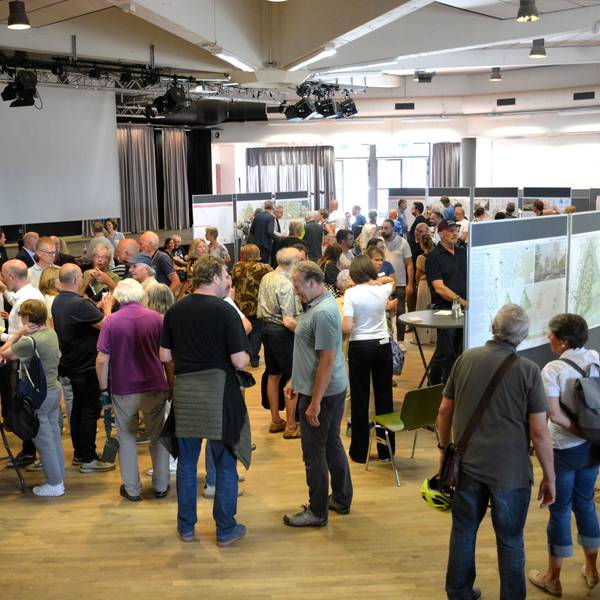 Viele Menschen stehen vor Infotafeln und sprechen miteinander.