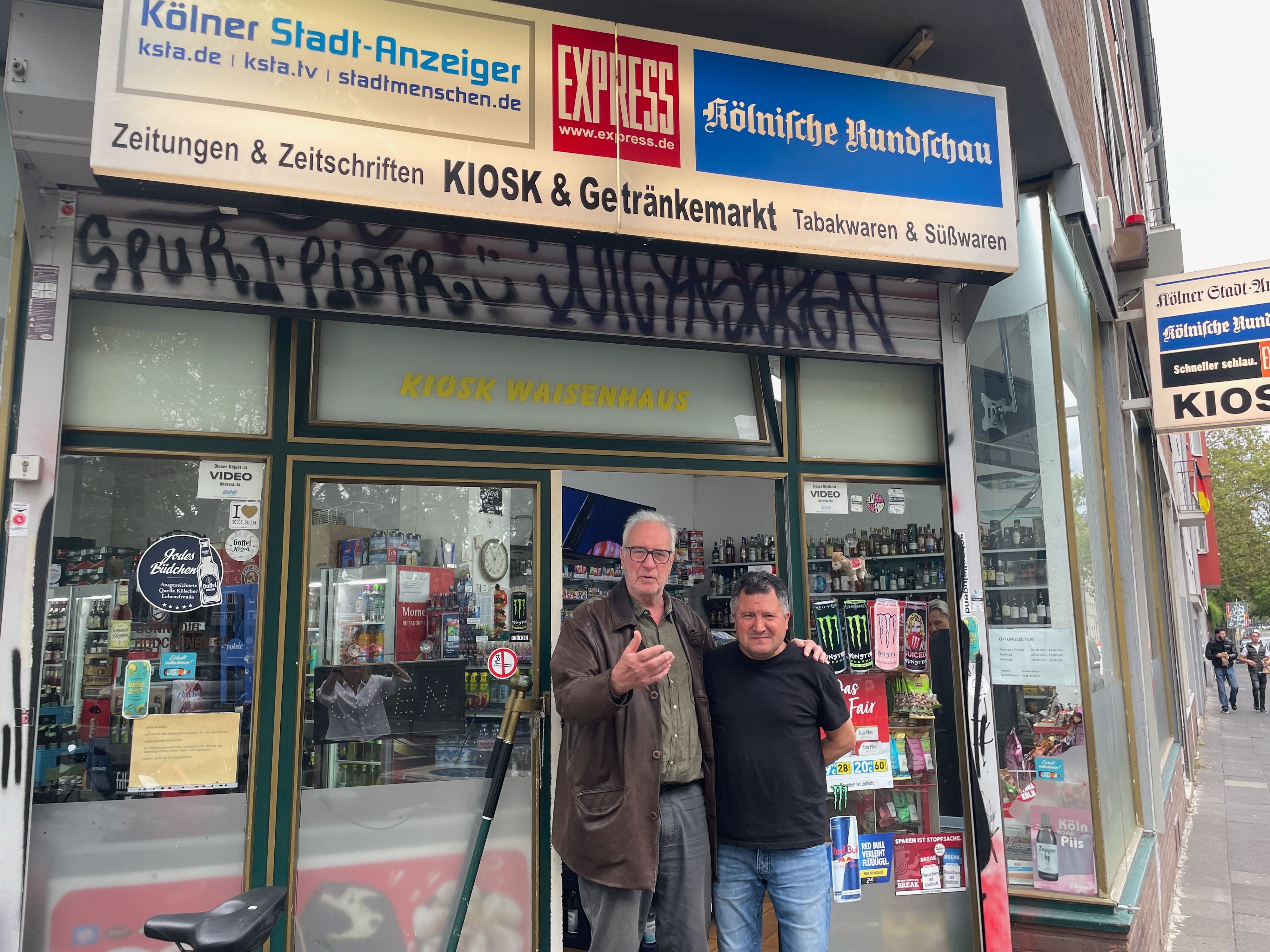 Zwei Männer stehen in der Tür eines Kiosks.