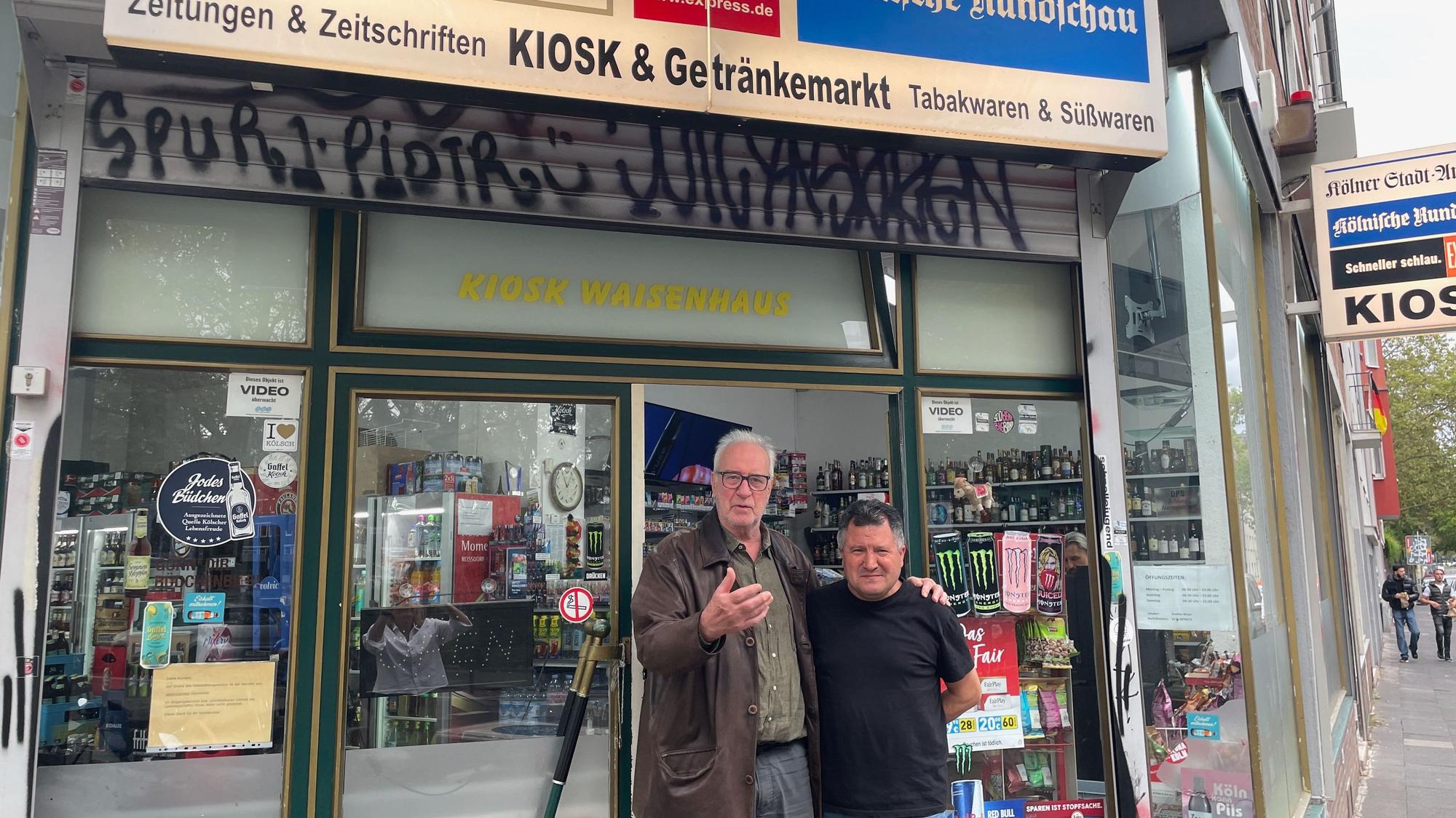 Zwei Männer stehen in der Tür eines Kiosks.