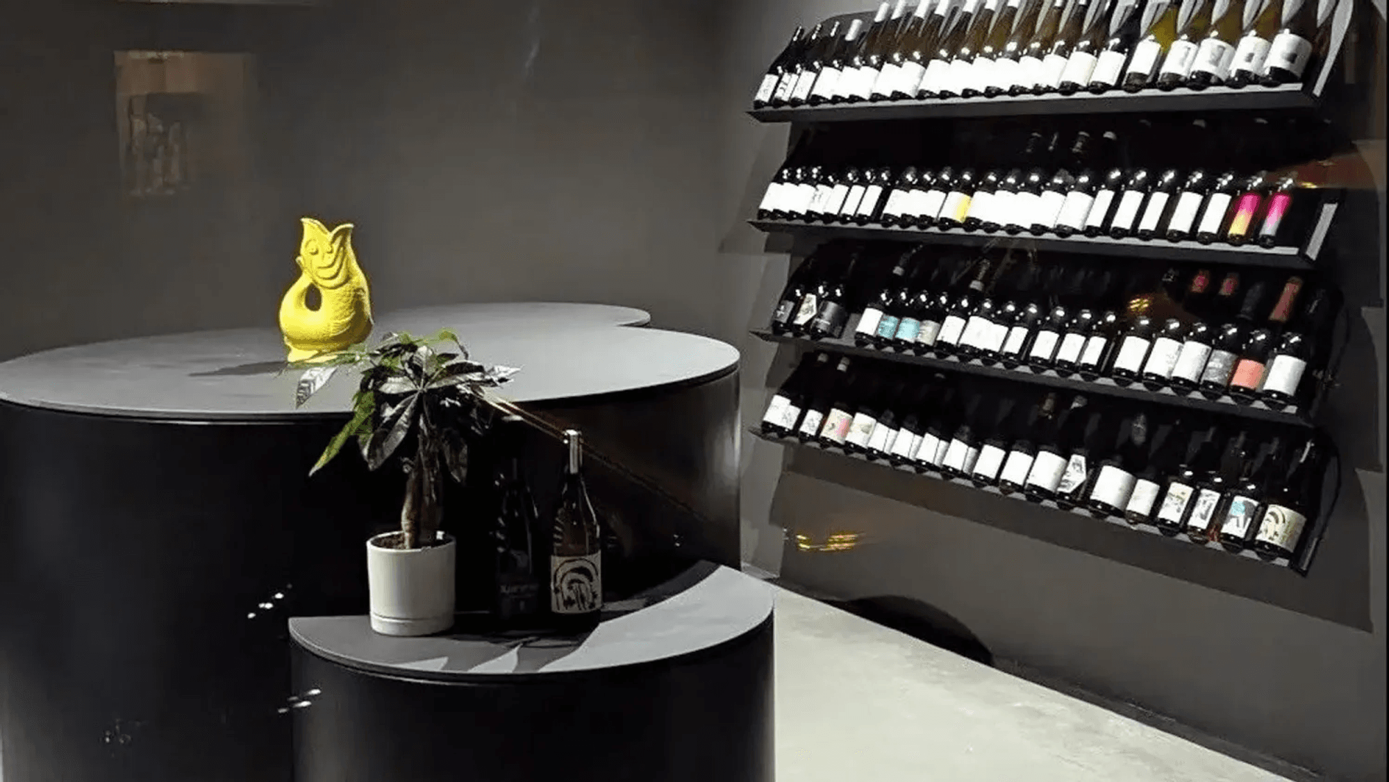 Ein schwarzer Raum mit Tischen und einem Weinregal.