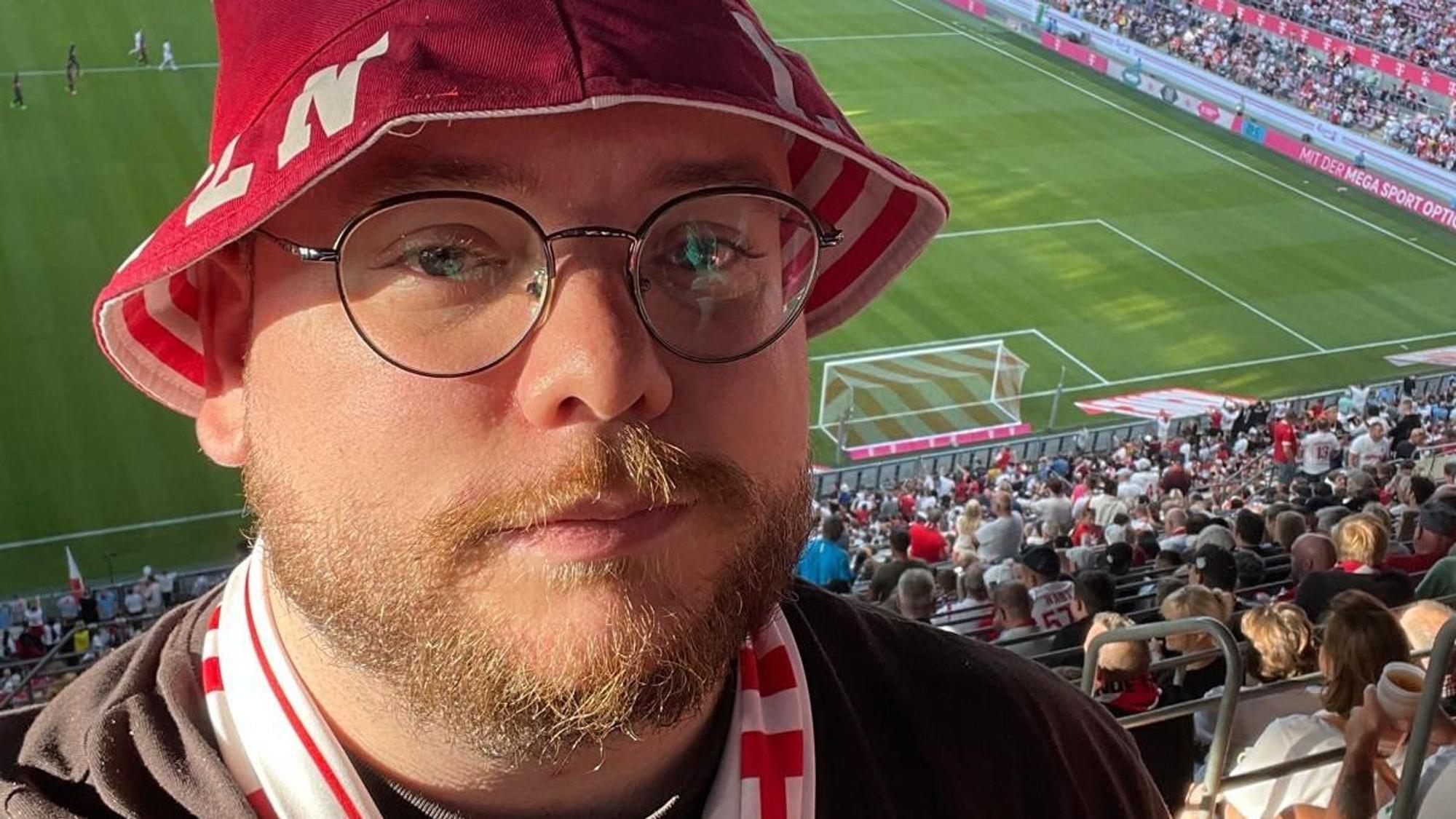 Das Foto zeigt Tobias Wolff mit Kappe und Schal auf der Tribüne.