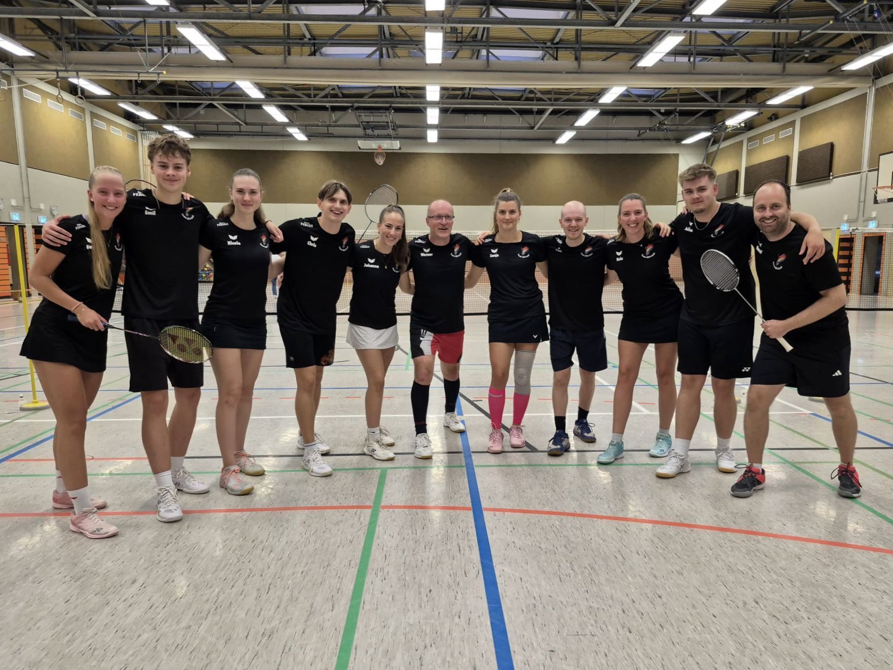 Die Badmintonspieler aus Kall stehen in einer Sporthalle.