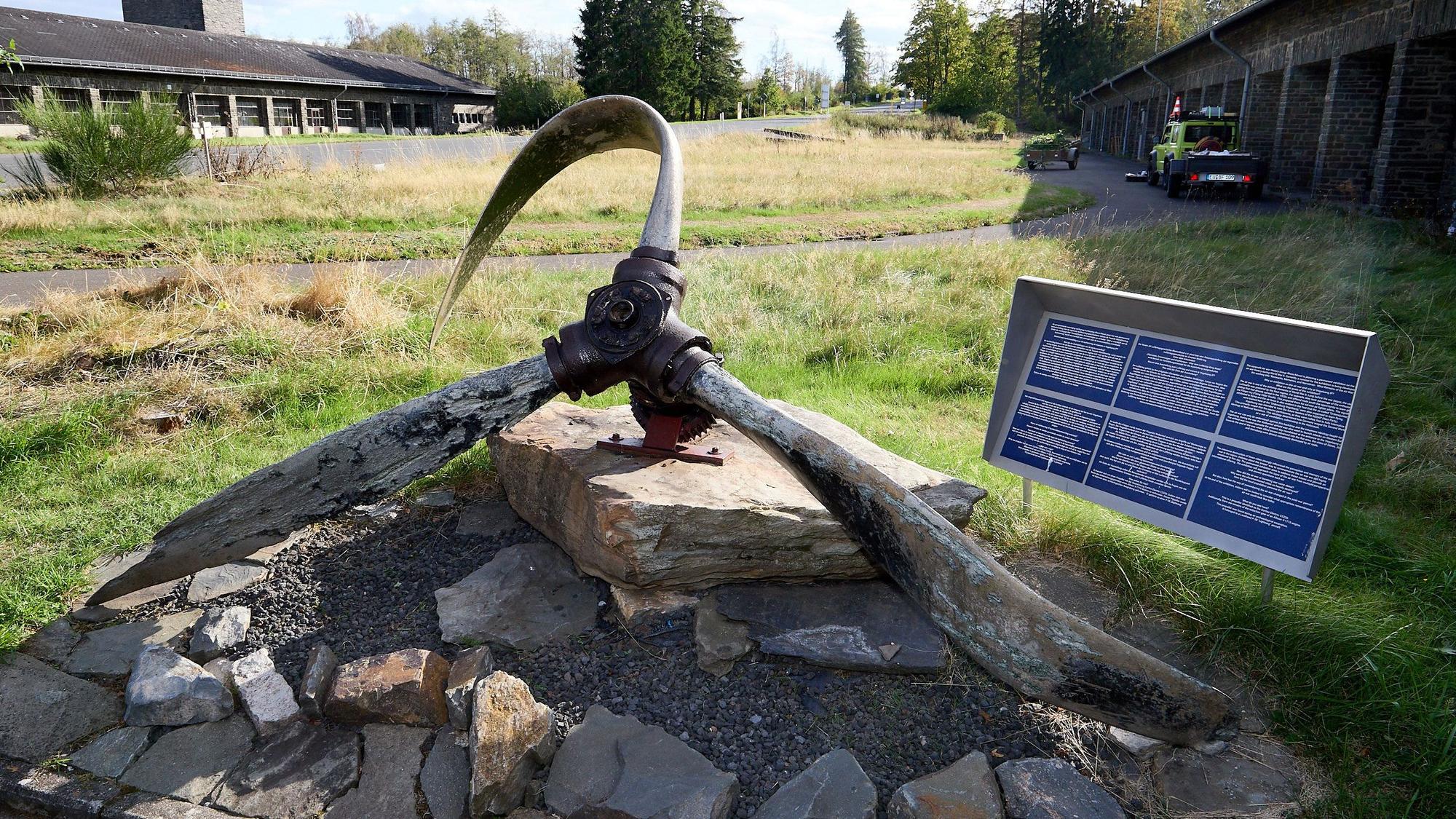 Ein verbogener Propeller einer P38 Lightning liegt auf einem großen Stein.