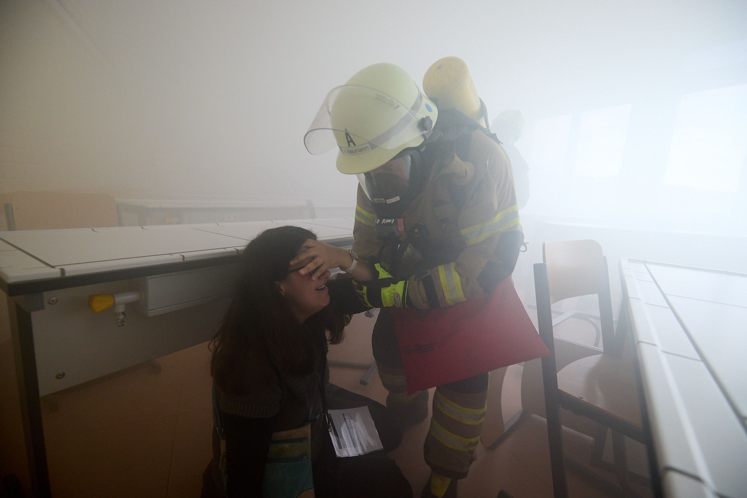 Im Nebel hat ein Feuerwehrmann eine Verletzten gefunden und bringt sie in Sicherheit.