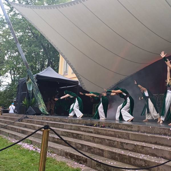 Schauspieler spielen auf einer Treppe unter einem Zeltdach.