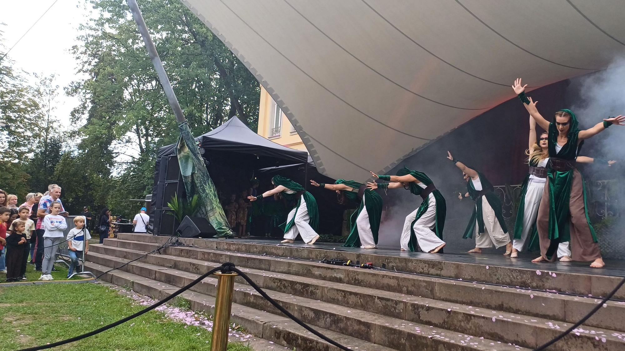 Schauspieler spielen auf einer Treppe unter einem Zeltdach.