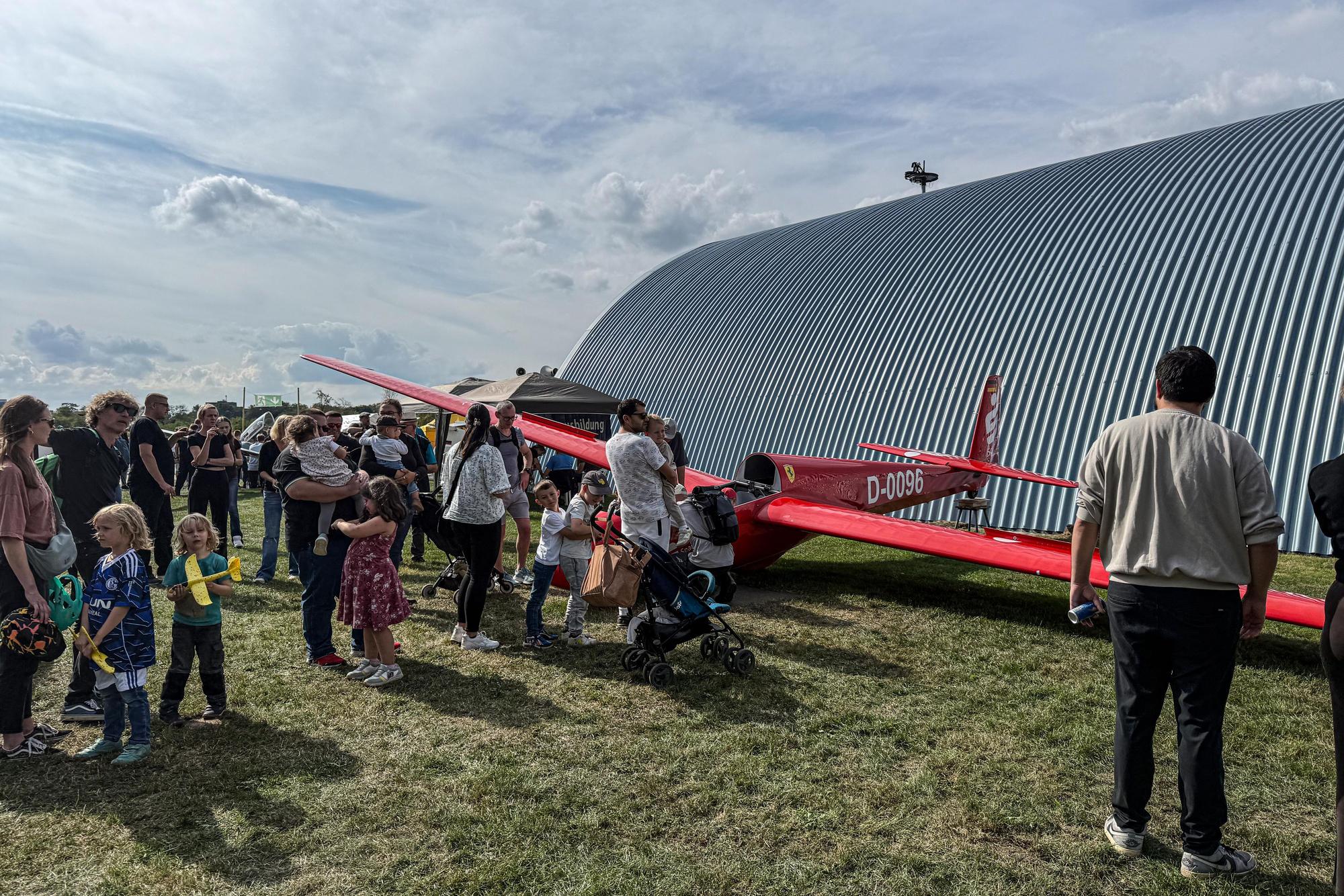 Besucher betrachten ein Segelflugzeug.