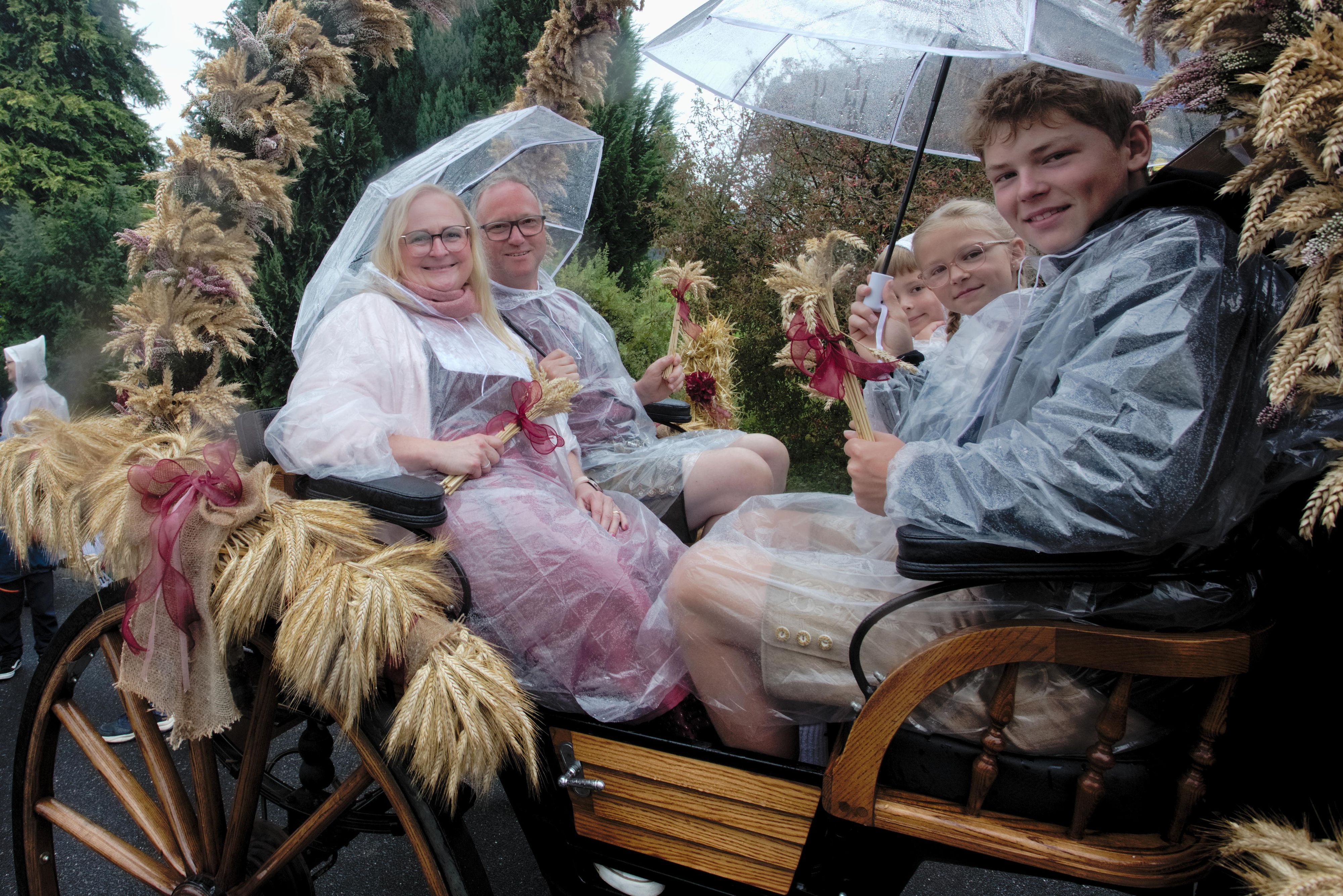 Das Erntepaar Rabea und Thorsten Reuter hat sich mit Capes und Regenschirmen gegen den Regen gewappnet.